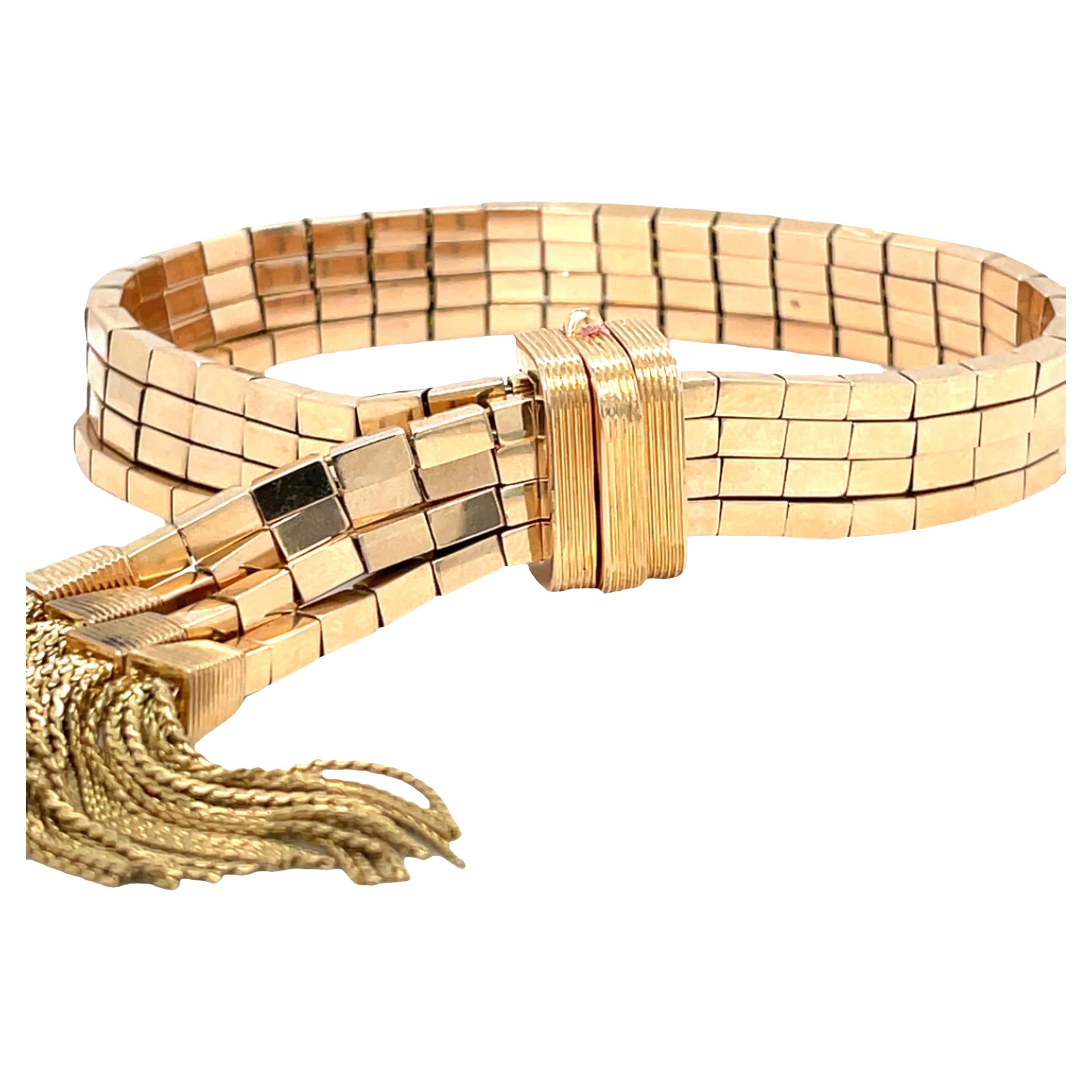 Questo bracciale è uno splendido esempio di design di metà secolo. Presenta quattro file di maglie rettangolari che avvolgono graziosamente il polso. Le estremità del bracciale sono ornate da una nappina composta da catene multiple, che aggiunge