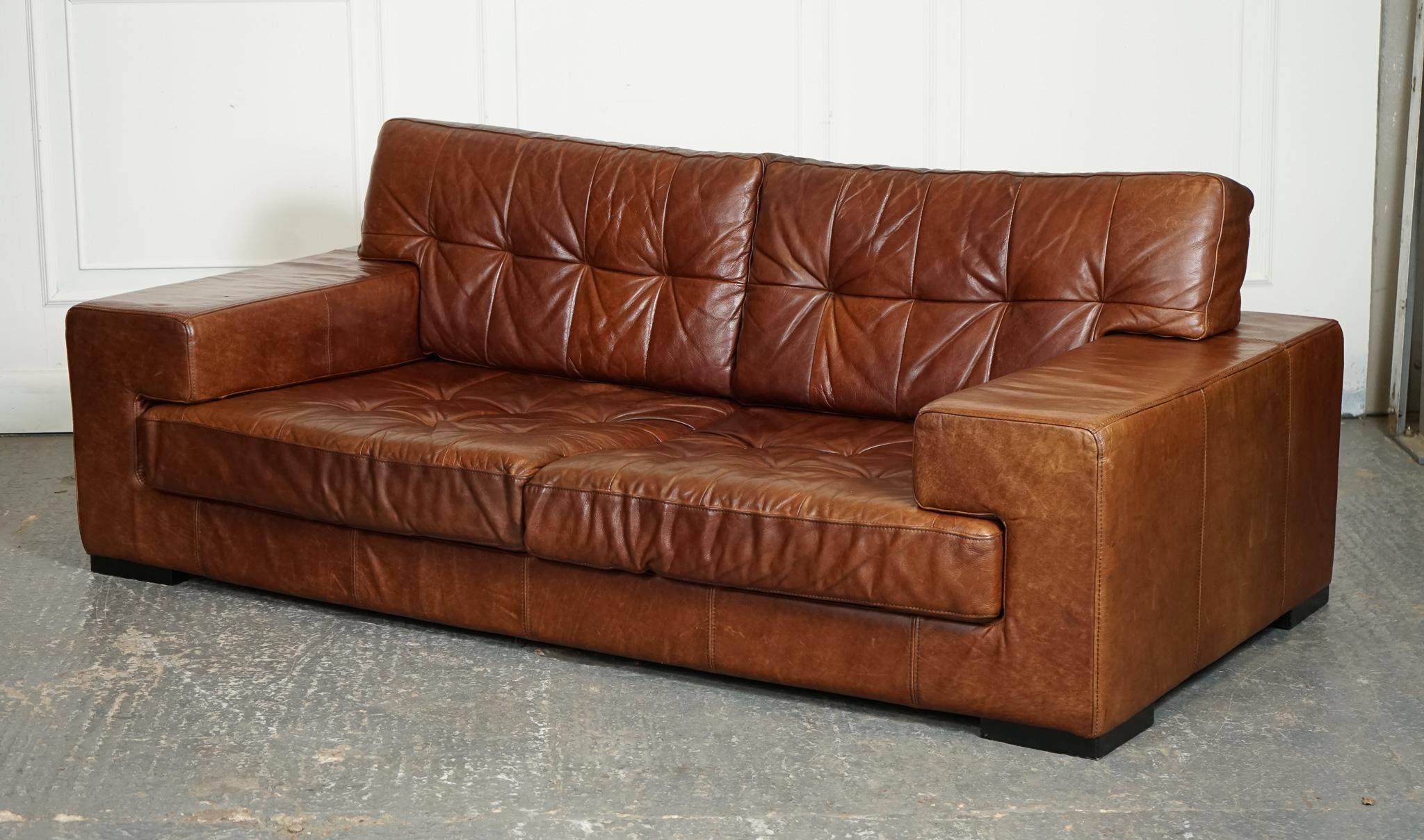 
Nous sommes ravis d'offrir à la vente ce magnifique canapé rétro en cuir brun Halo Timothy Oulton.

Le canapé en cuir marron Retro Halo Timothy Oulton est un meuble élégant et luxueux qui associe des éléments de design rétro au confort moderne.  Le