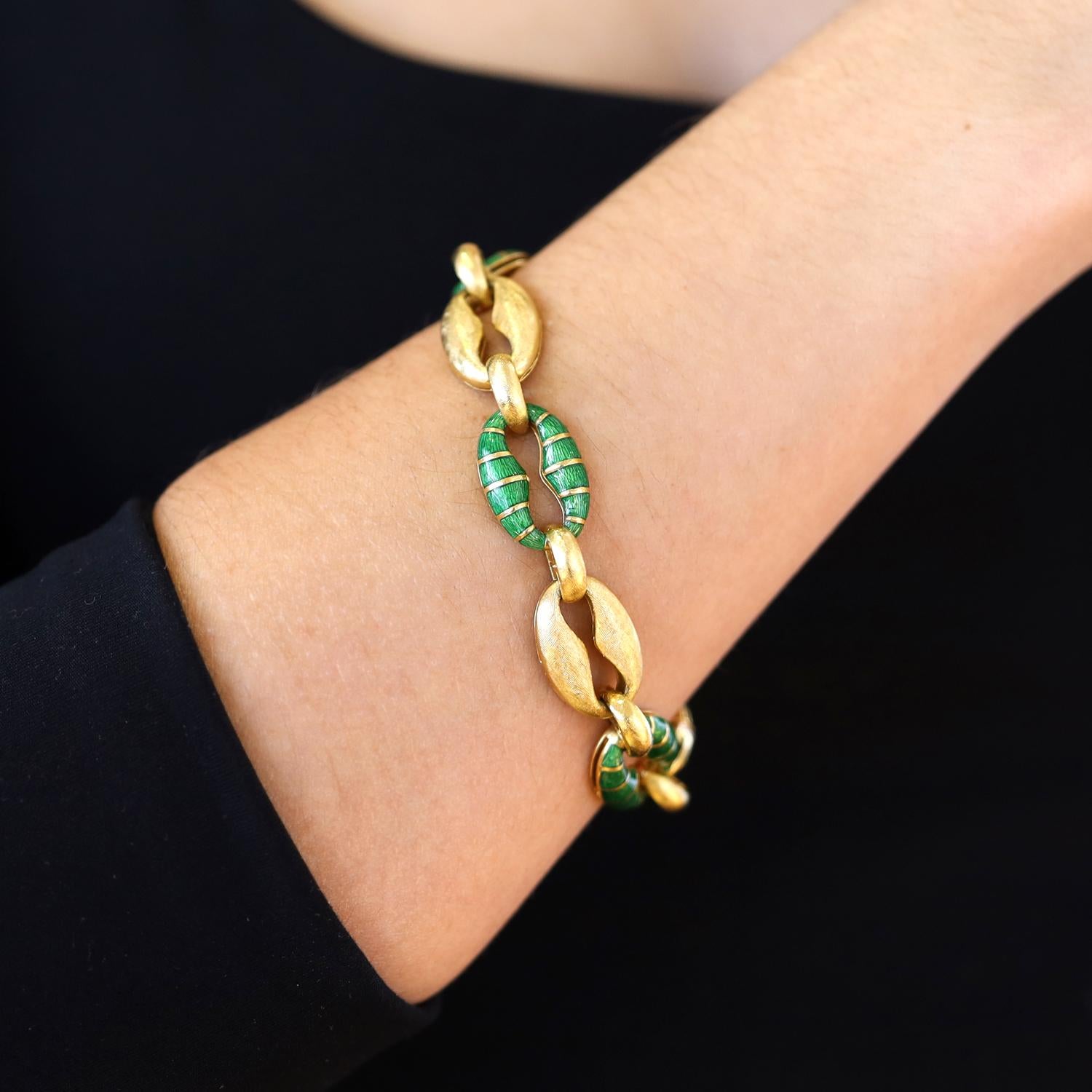 Questo squisito bracciale a maglie mette in mostra un'armoniosa miscela di sontuoso oro 18 carati e vibrante smalto verde. Realizzato in Italia, questo pezzo di design presenta maglie alternate di oro liscio e smalto dalle tonalità intense, un