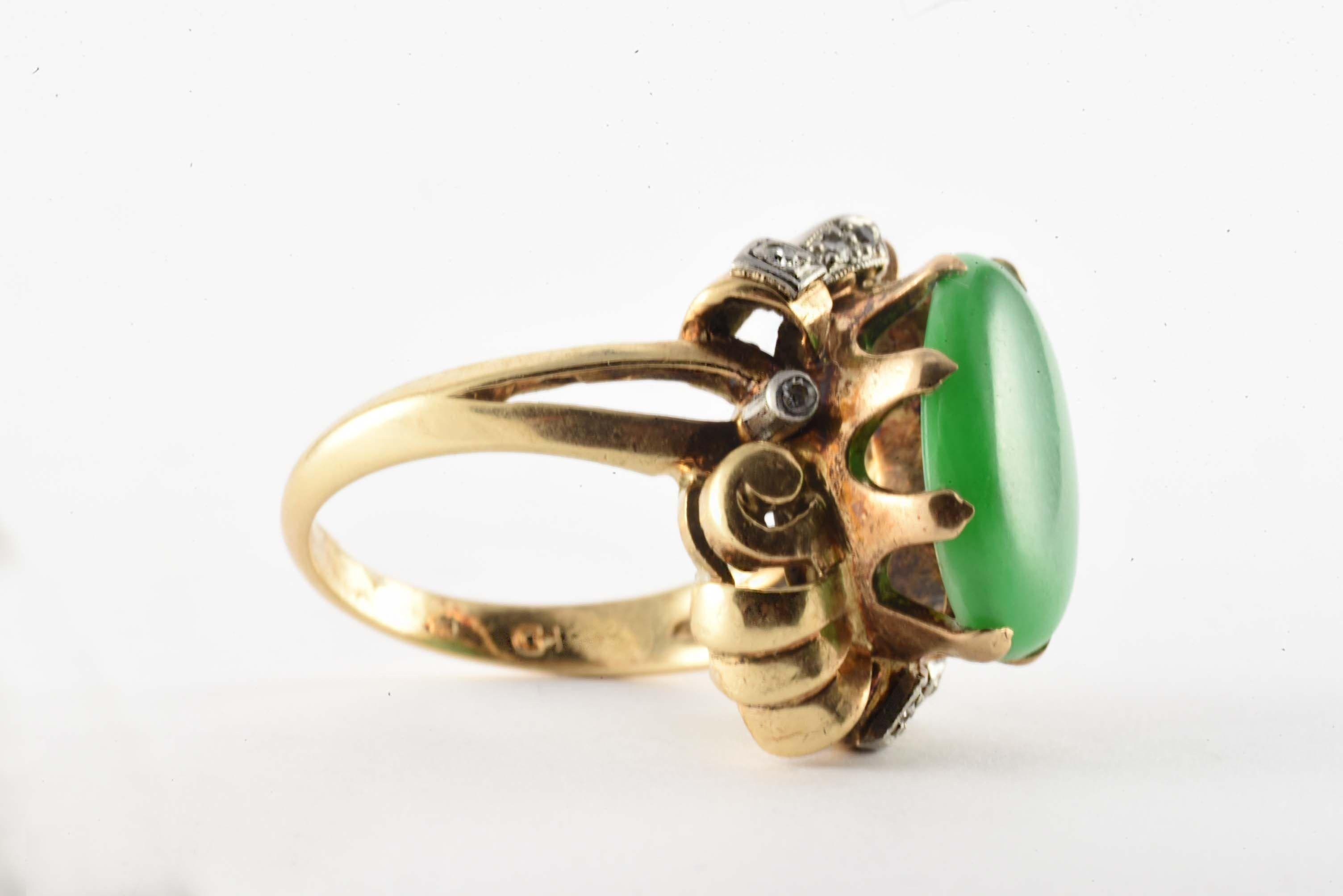 Este anillo vintage de la época Retro, que data de la década de 1940, presenta un Jade de nefrita verde de forma ovalada que mide 10,9 x 14,1 mm, acentuado con ocho diamantes de talla única, color H-I, claridad SI-I1, que suman aproximadamente 0,10