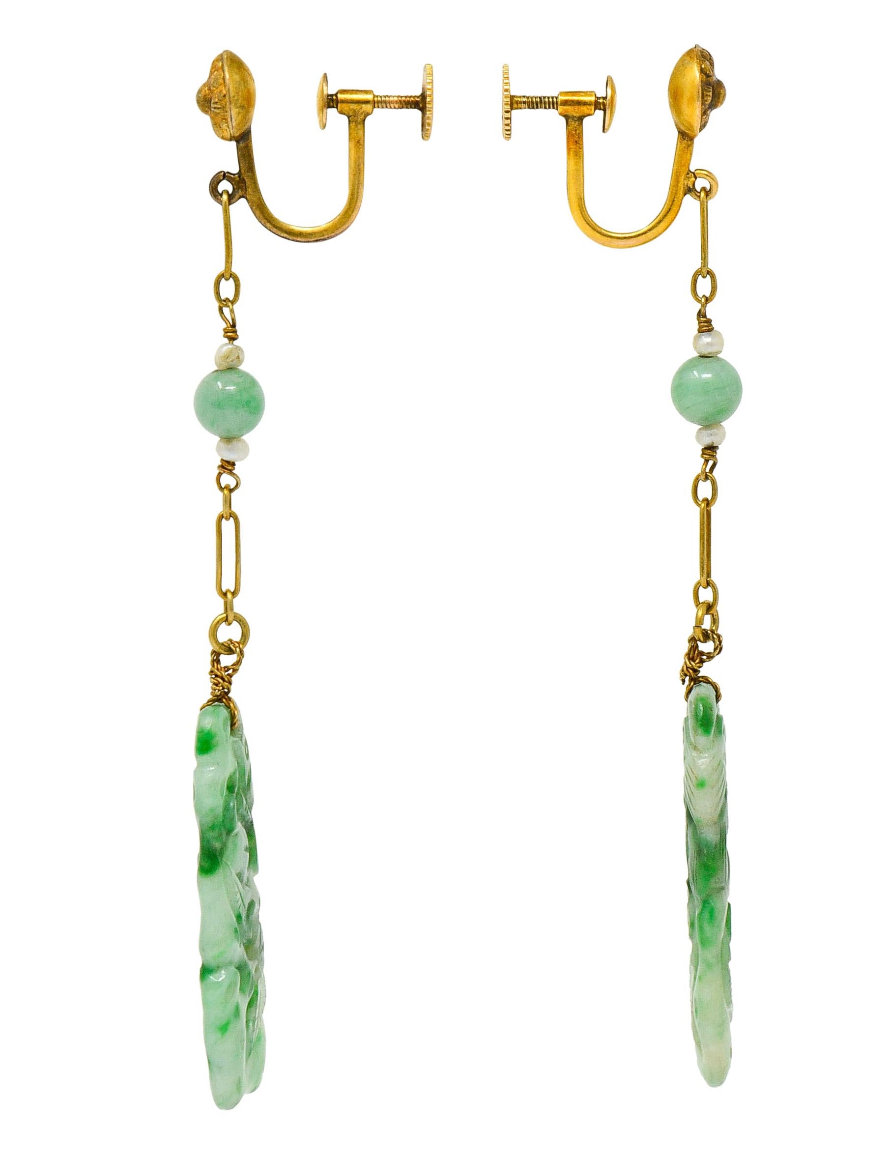 Screwbacks are designed with floral repoussè surmounts

Suspending elongated gold links and 4.9 mm round jade beads accented by 2.0 mm natural freshwater pearls

Terminating as an ornately carved rectangular tablet of jade

Strongly mottled dark