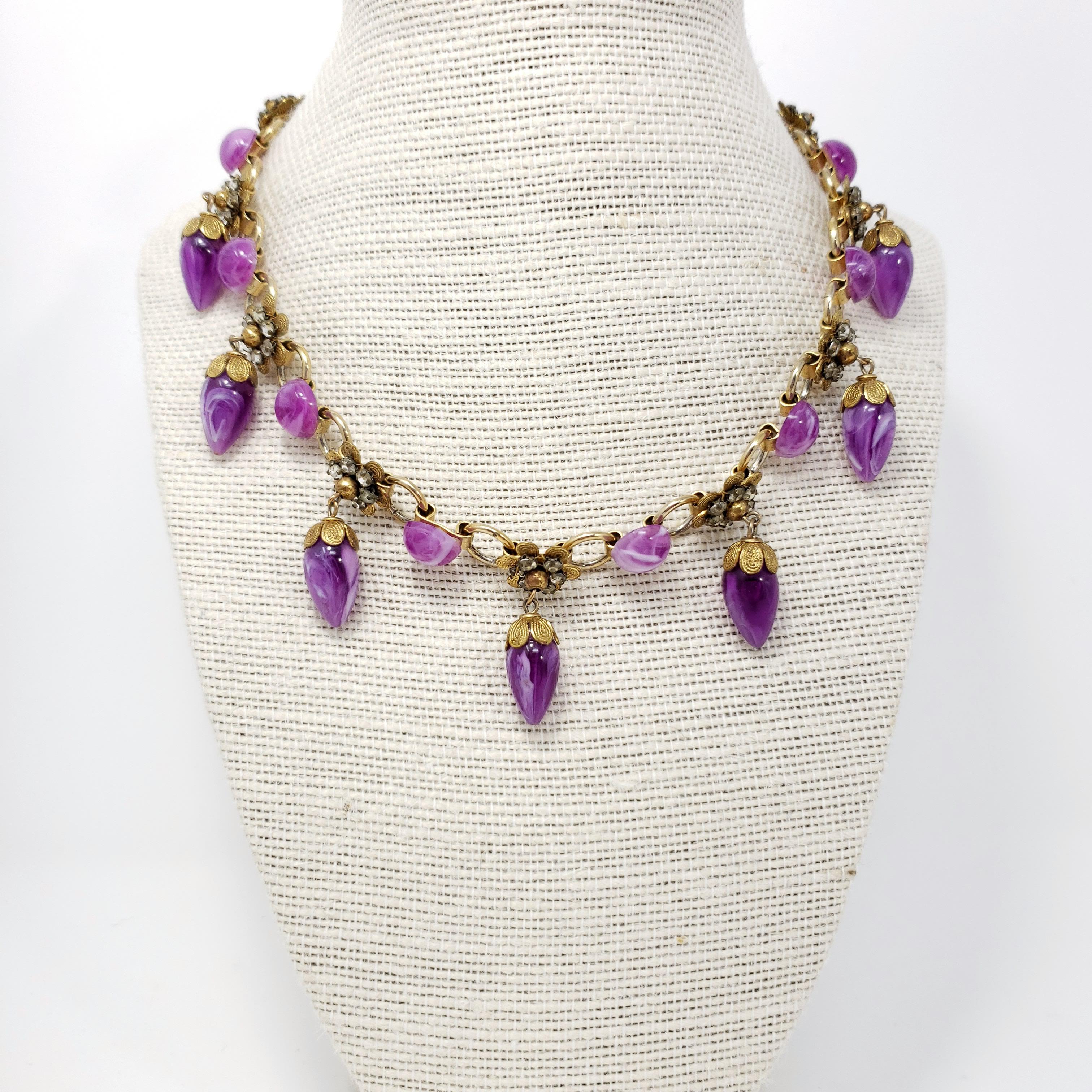 Retro floral necklace, featuring golden flower motifs accented with dangling violet crystals.

Gold-plated. Spring-ring clasp.