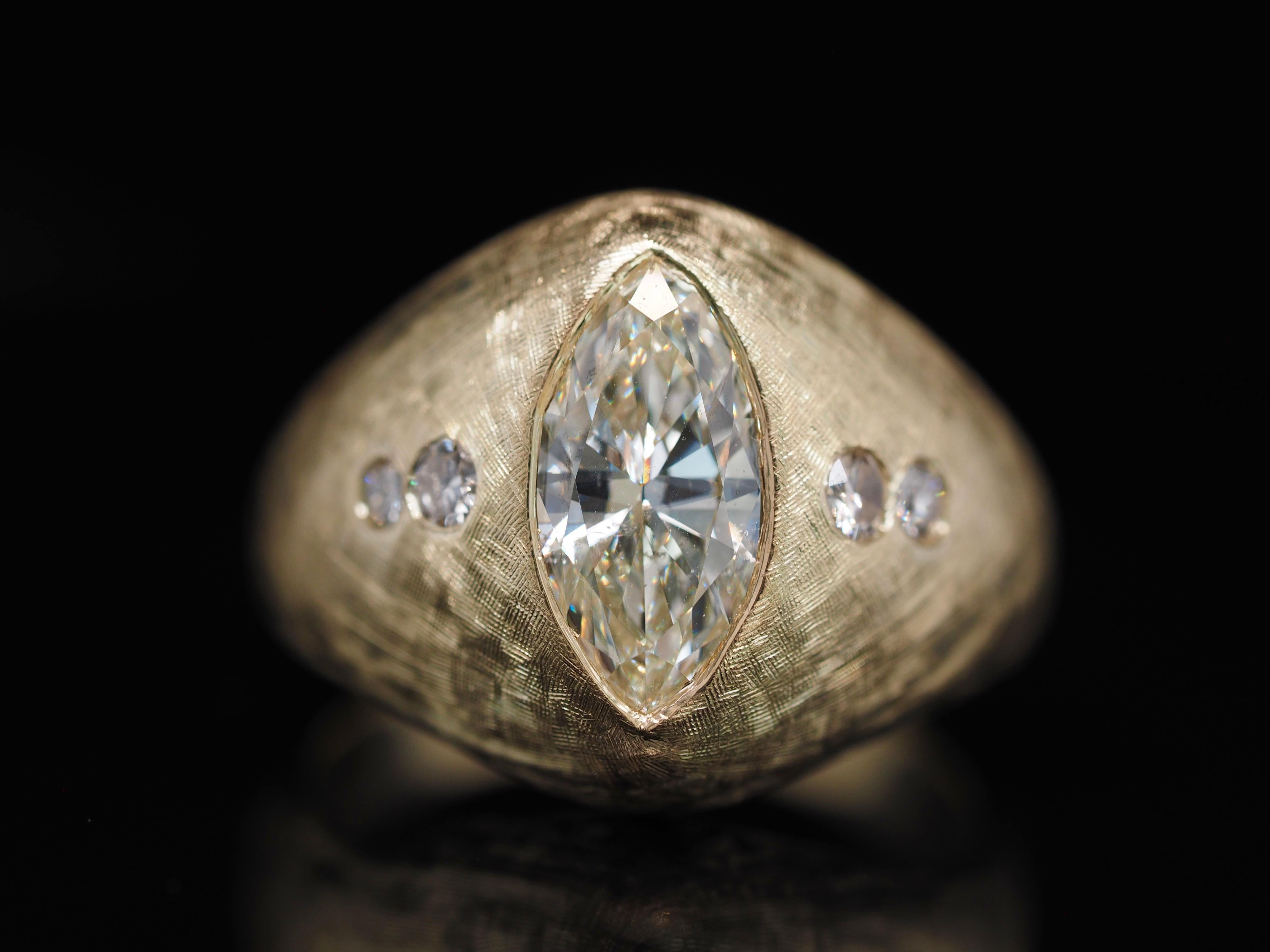 This retro ring is truly one of a kind!  It has an  incredible matte finish creating the perfect contrast between the diamonds and metal. The Center is an incredible 2.10ct Marquise diamond, with accented diamonds on both ends.  A sleek deign that