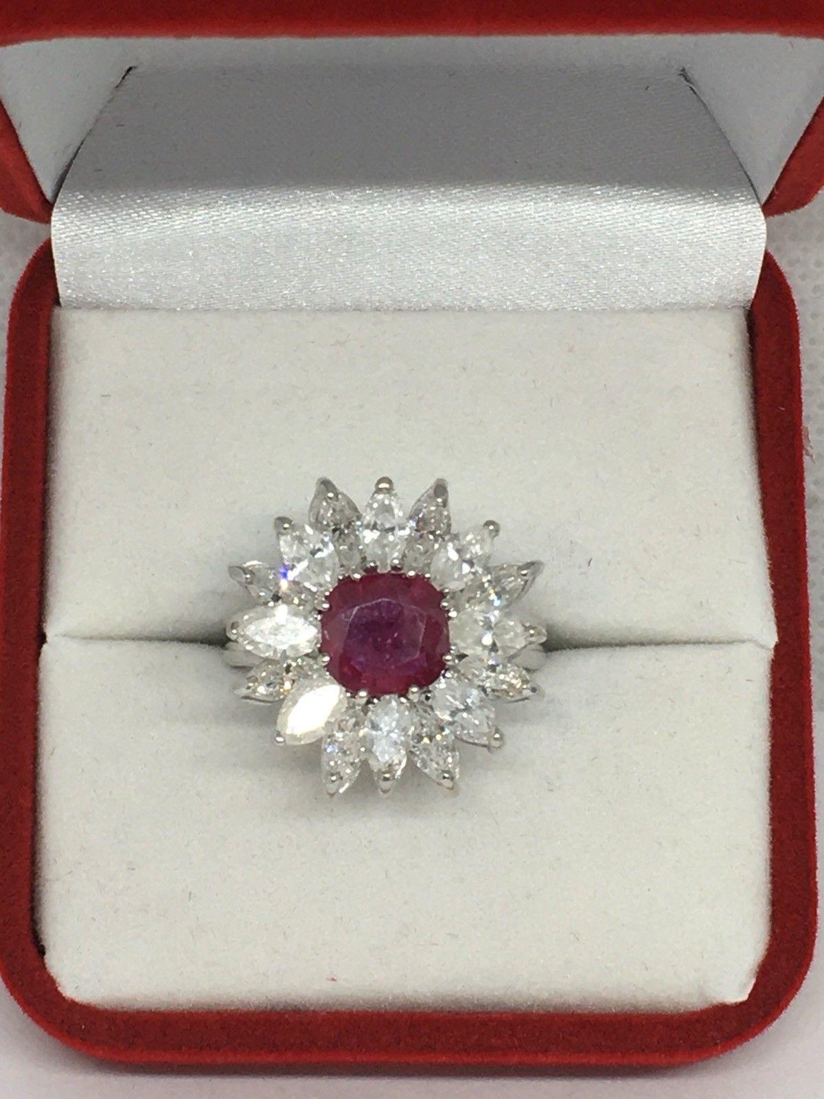 This stunning estate ring is set in 14k white gold with a stunning genuine red cushion cut ruby, total approximate weight of the ruby is 1.80 carats.

Surrounding the ruby in a flower style halo are over 2.50 carats of beautiful large white marquis