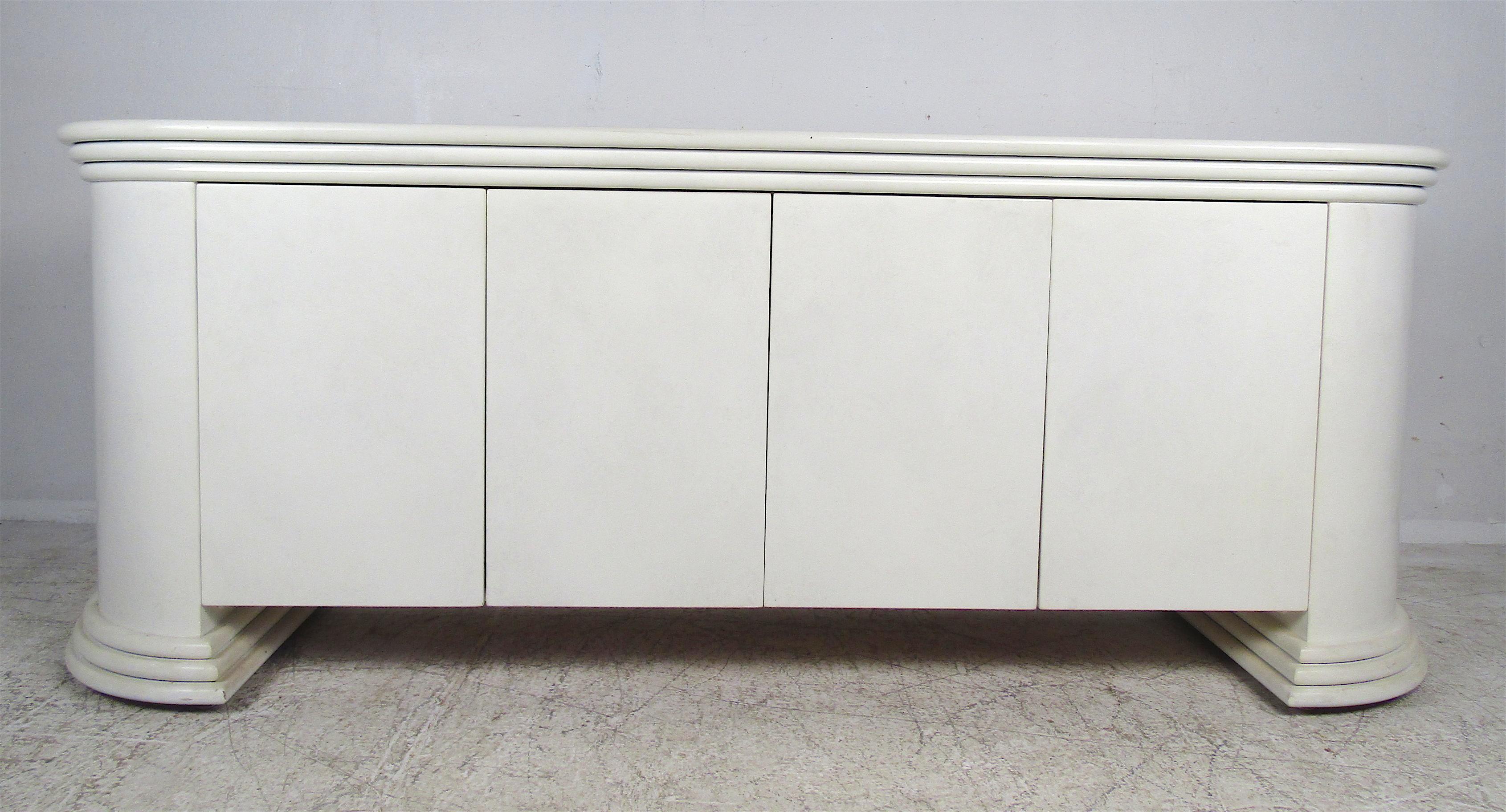 This remarkable vintage modern sideboard features plenty of room for storage. A lovely Karl Springer style lacquered casing with a decorative base and top edges. Four swinging cabinet doors open up to unveil plenty of space for storage with shelves