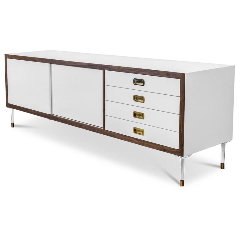 Introducing our new St. Martin Credenza featuring two sliding doors and four drawers to maximize its functionality while still being stylish and chic. This retro-modern design features an oiled walnut trim, brass hardware, our famous White lacquer