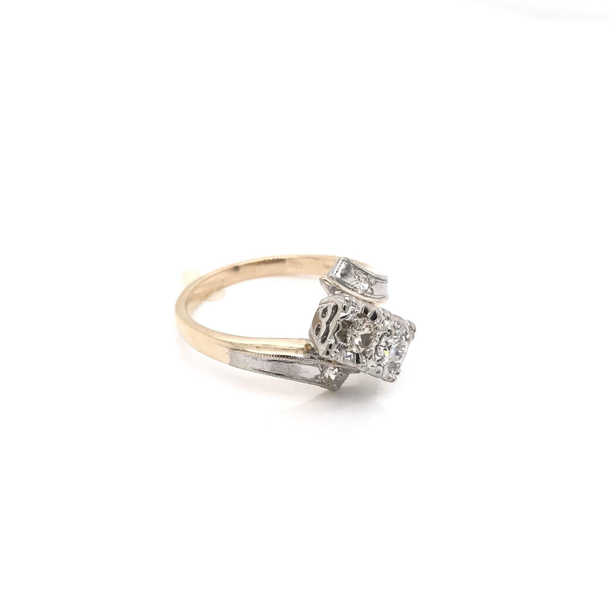 This piece was crafted sometime during the Mid Century design period ( 1940-1960 ). This ring features a lovely two toned 14k white gold and gold setting. The piece features two diamonds set in the classic 