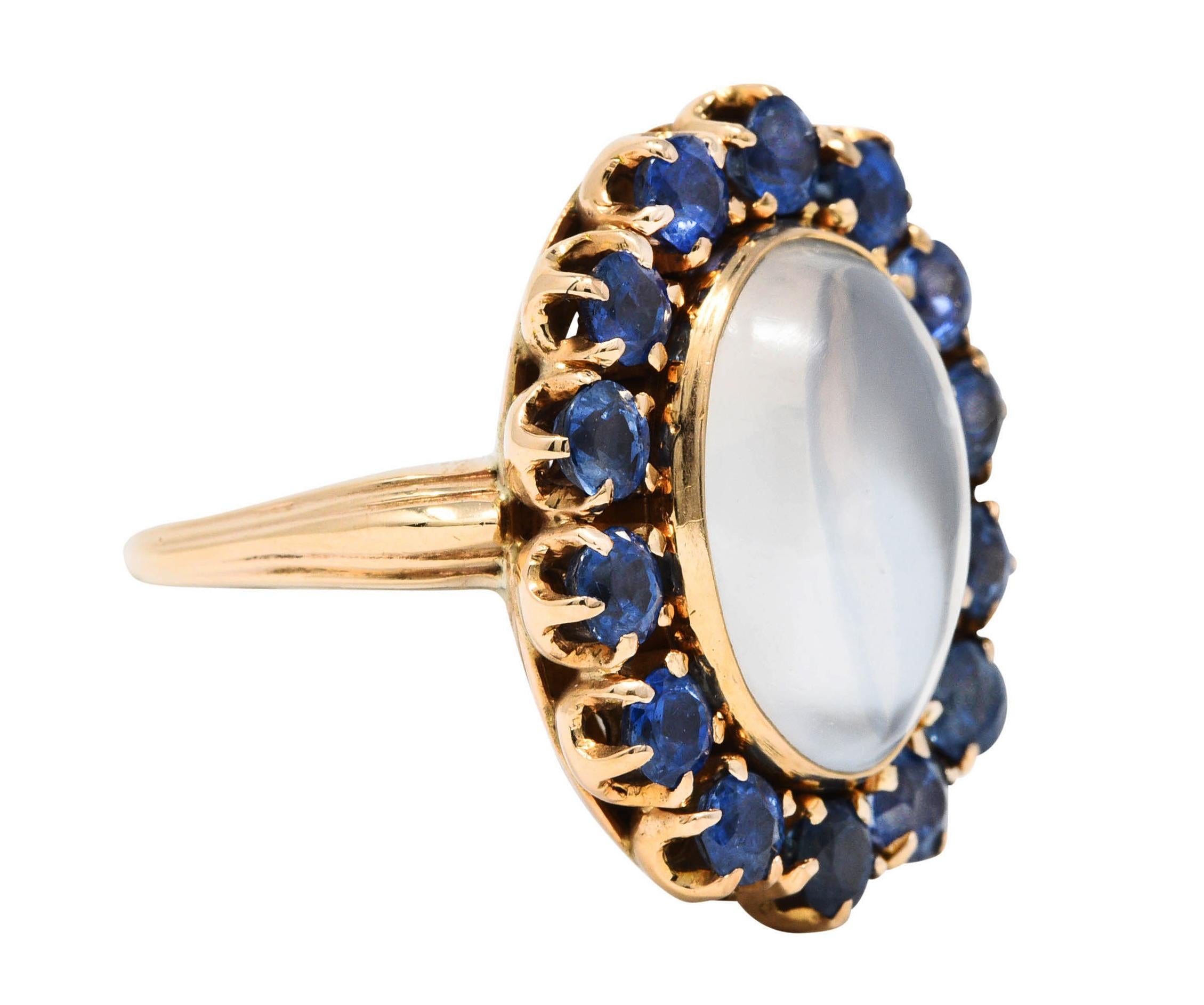 Cluster ring centers an oval moonstone cabochon measuring approximately 13.8 x 9.5 mm

Translucent with strong billowing white adularescence

Surrounded by a halo of round cut sapphires - prong set

A well matched cornflower blue while weighing in