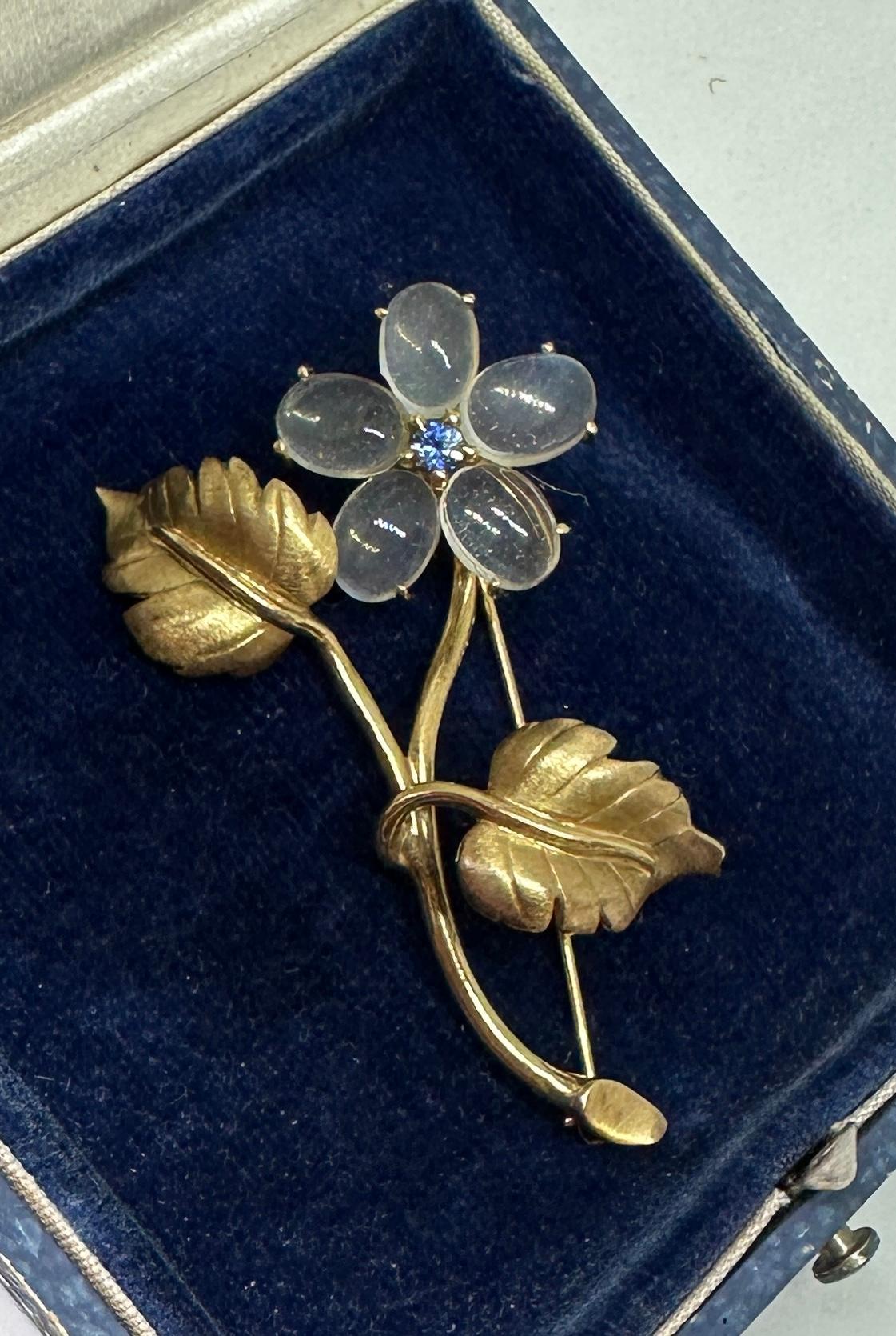 This is a gorgeous and rare antique Moonstone and Sapphire Flower Brooch Pin in 14 Karat Gold.  The stunning jewel is an Antique brooch dating to the Mid-Century Modern period.  It is in the style of the Cartier and Tiffany flower brooches.  The