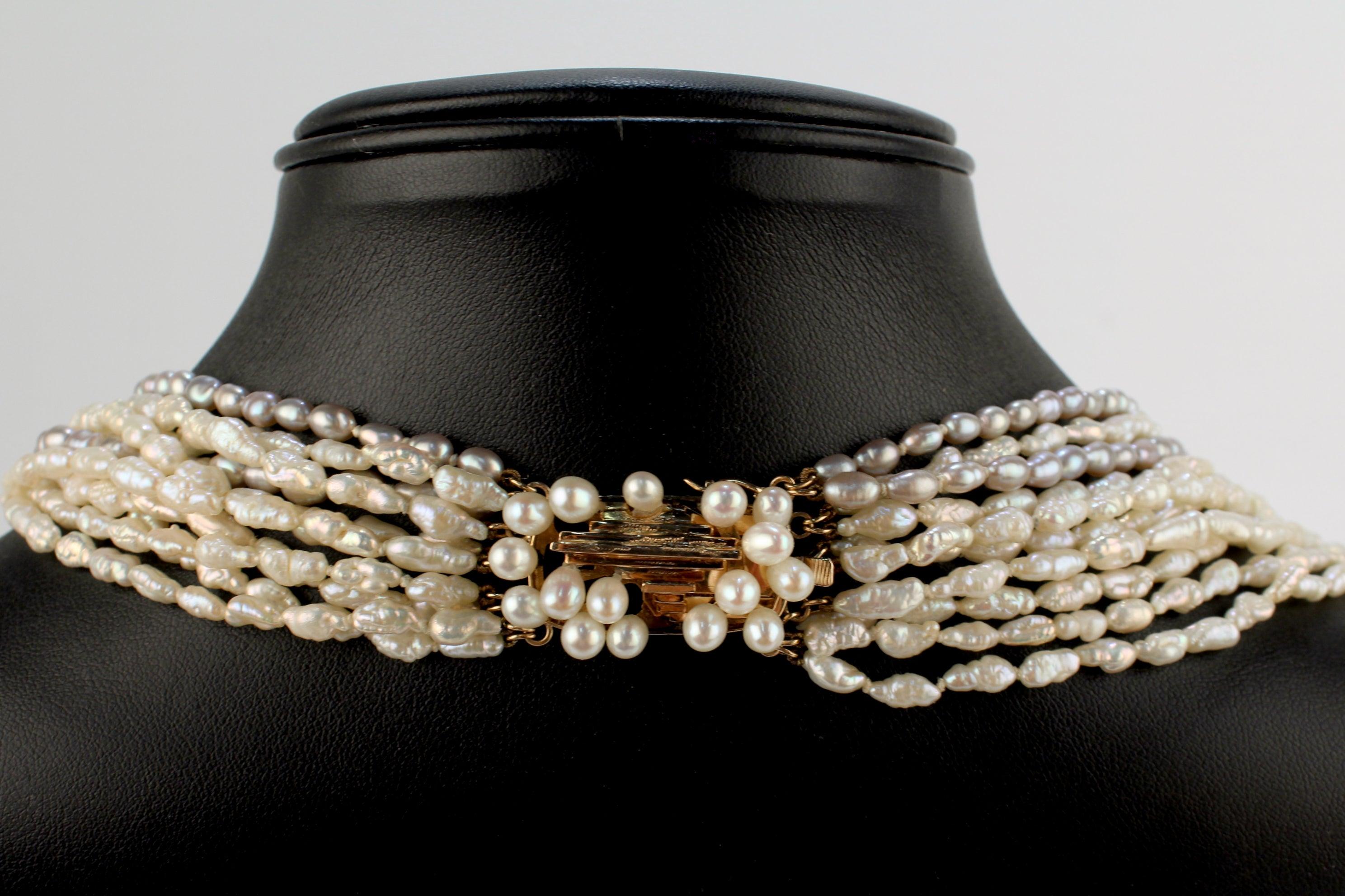 A very fine multi-strand freshwater pearl necklace with a Brutalist 14k gold clasp.

With elongated grey and white freshwater pearls hand-knotted on silk cord. 

Having a modern box clasp with a stepped gold top that is punctuated by additional