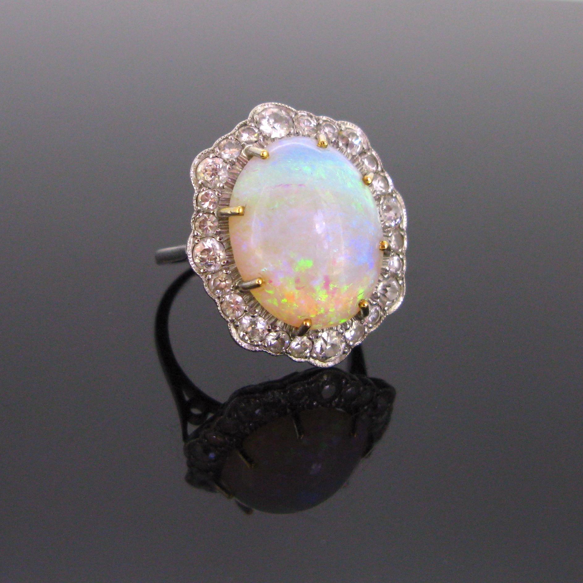 This beautiful ring features an opal weighing over 10ct and is surrounded by 26 old European cut diamonds of varying sizes weighing approximately in total 1.90ct. The fires in this opal are lively and vibrant. Opal is the birthstone for the month of