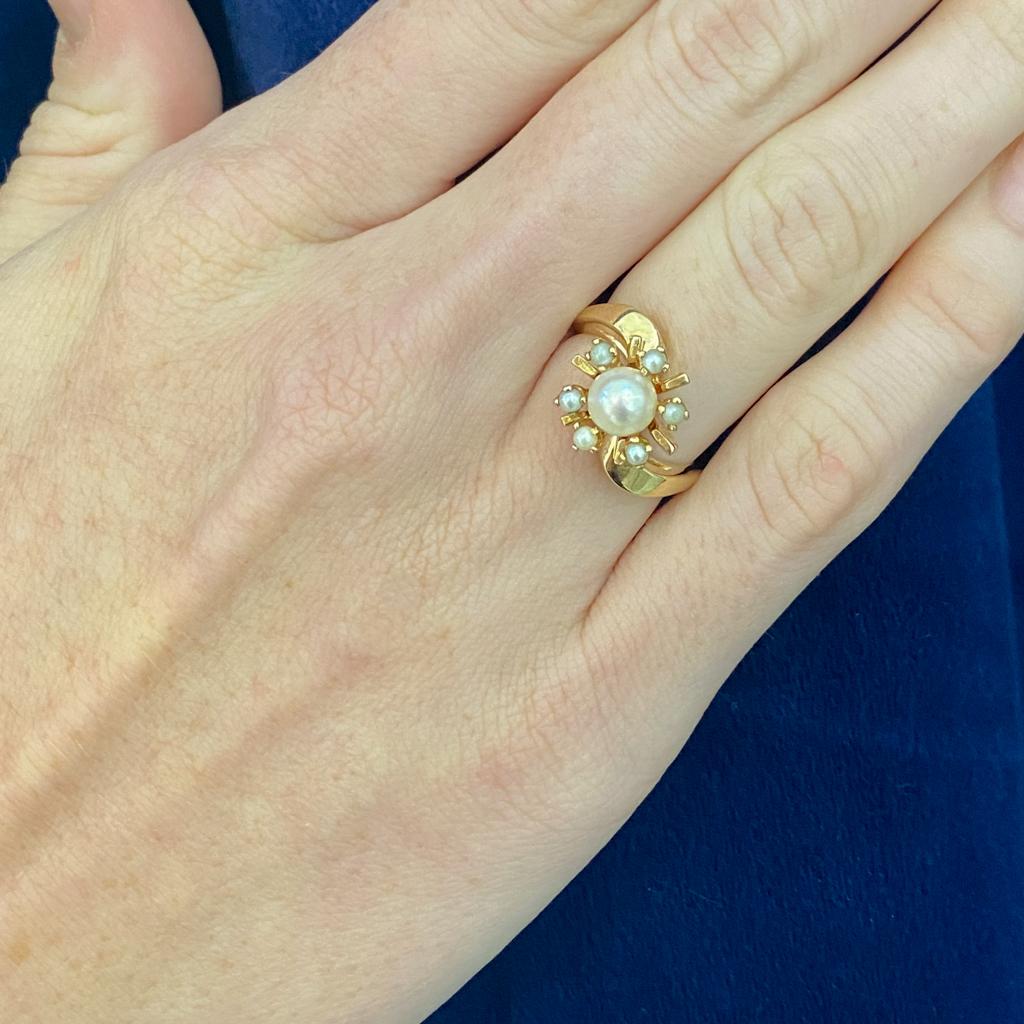 Cette fabuleuse bague vintage présente un style sputnik rétro classique des années 1950. De petites perles de culture alternent avec des ailettes d'or entourant la gracieuse perle centrale. Portez un morceau d'histoire, célébrez votre amour de