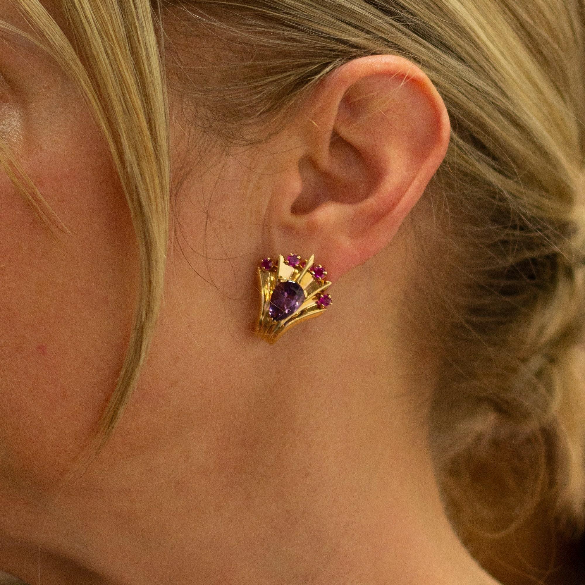 A wonderful pair of 18 karat yellow gold pierced ear clips in the form of peacock fans. The tips of each 'fan' are set with four yellow gold claw settings which each contain a brilliant cut pink red ruby and below which sits a single pear cut