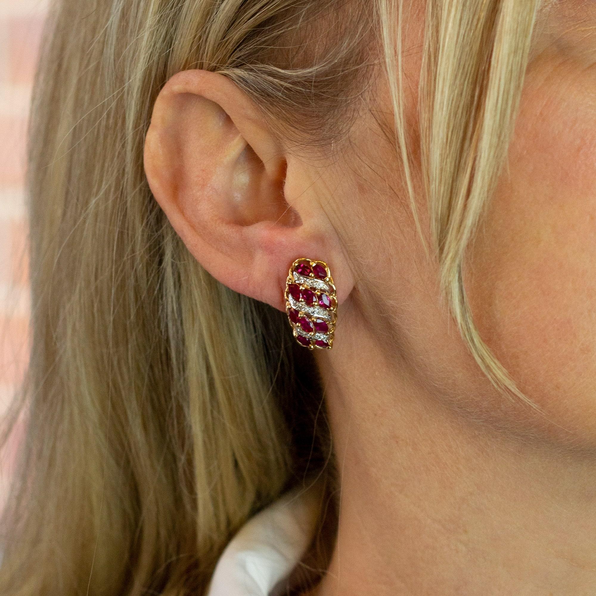 A wonderful pair of mid century 14 karat gold, ruby and diamond screw back earrings. The two tone earrings comprise of marquise cut rubies which are accented with single cut diamonds which flow down the ear diagonally. The rubies and diamonds are