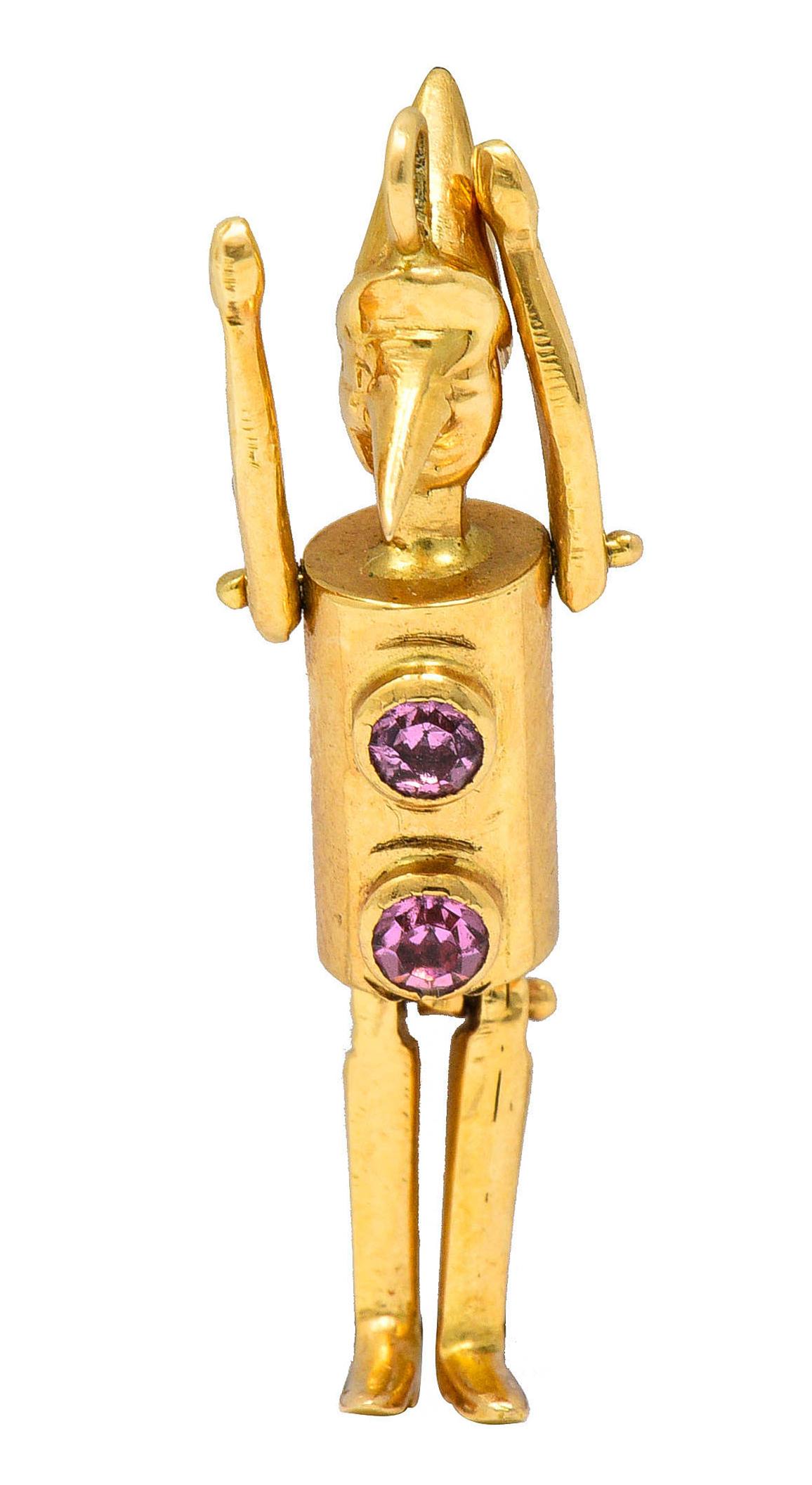 Charm is designed as Pinocchio with a polished gold finish

Centering two bezel set round cut pink sapphire weighing approximately 0.30 carat

With articulated arms and legs then topped by jump ring bale

Tested as 18 karat gold

Circa: