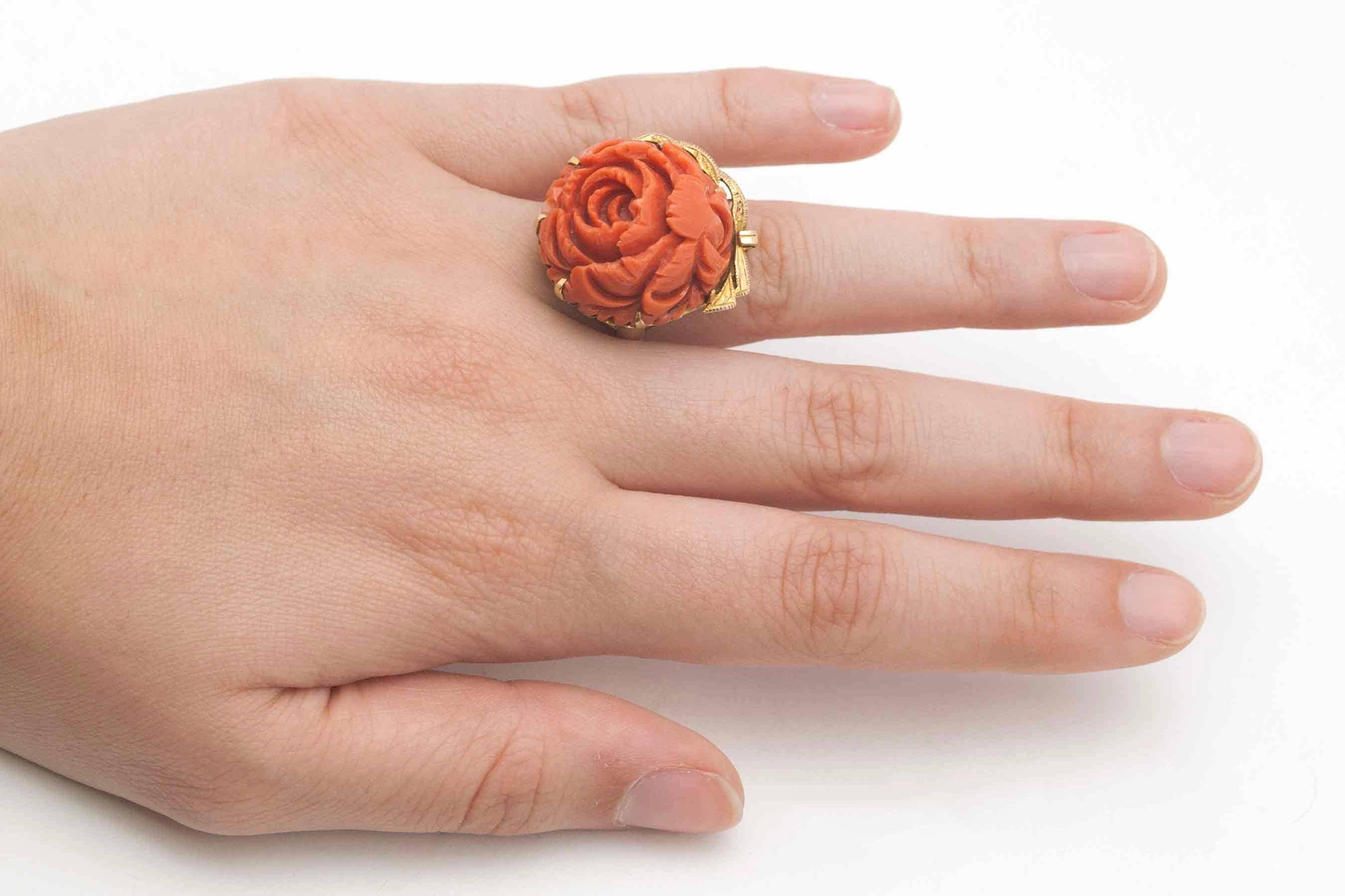 Centering on a finely carved natural coral rose or peony, this bold, Retro statement ring will surely elicit gasps from admirers. Coral of this color is scarce and will only increase in value. This unique heirloom cocktail ring will bring years of