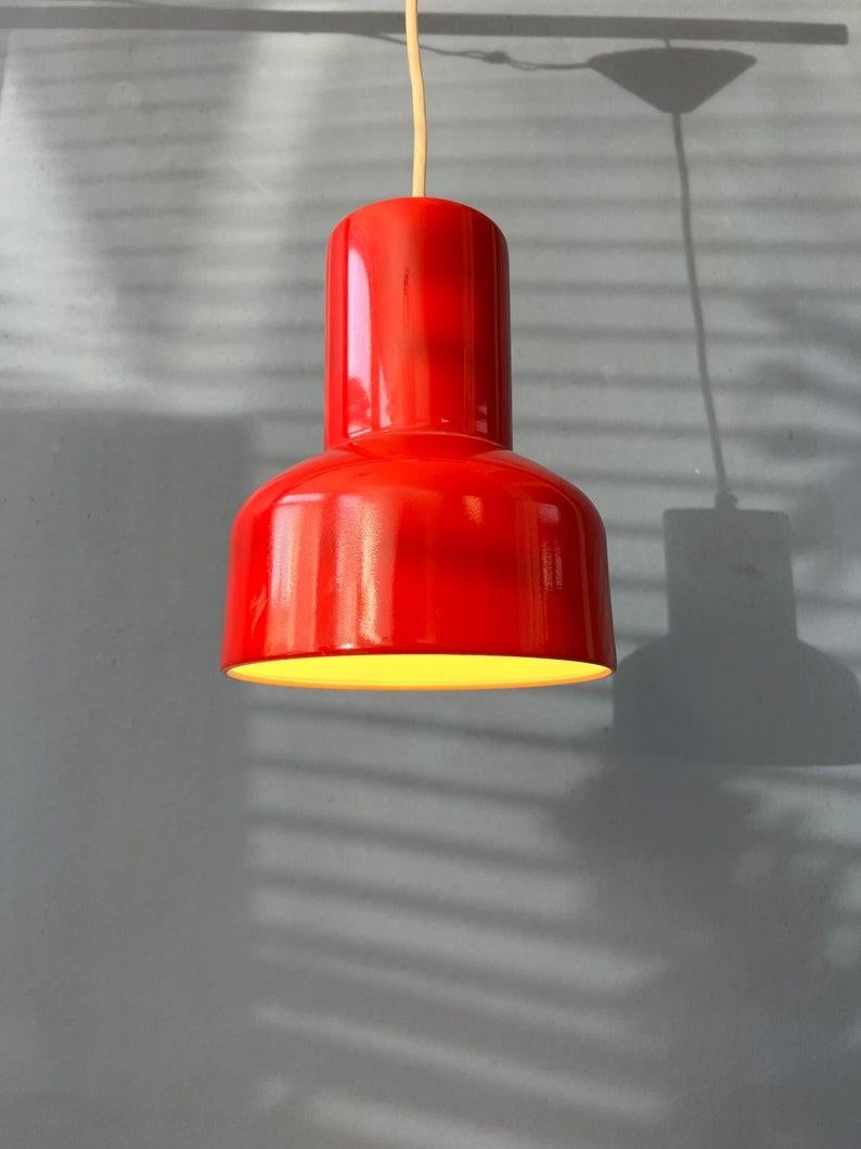 Red vintage space age pendant lamp made out of metal. The shade is nicely shaped and consists out of thick metal with red lacquer. The lamp requires one E27 lightbulb.

Additional information:
Materials: Metal
Period: 1970s
Dimensions: ø Shade: 11