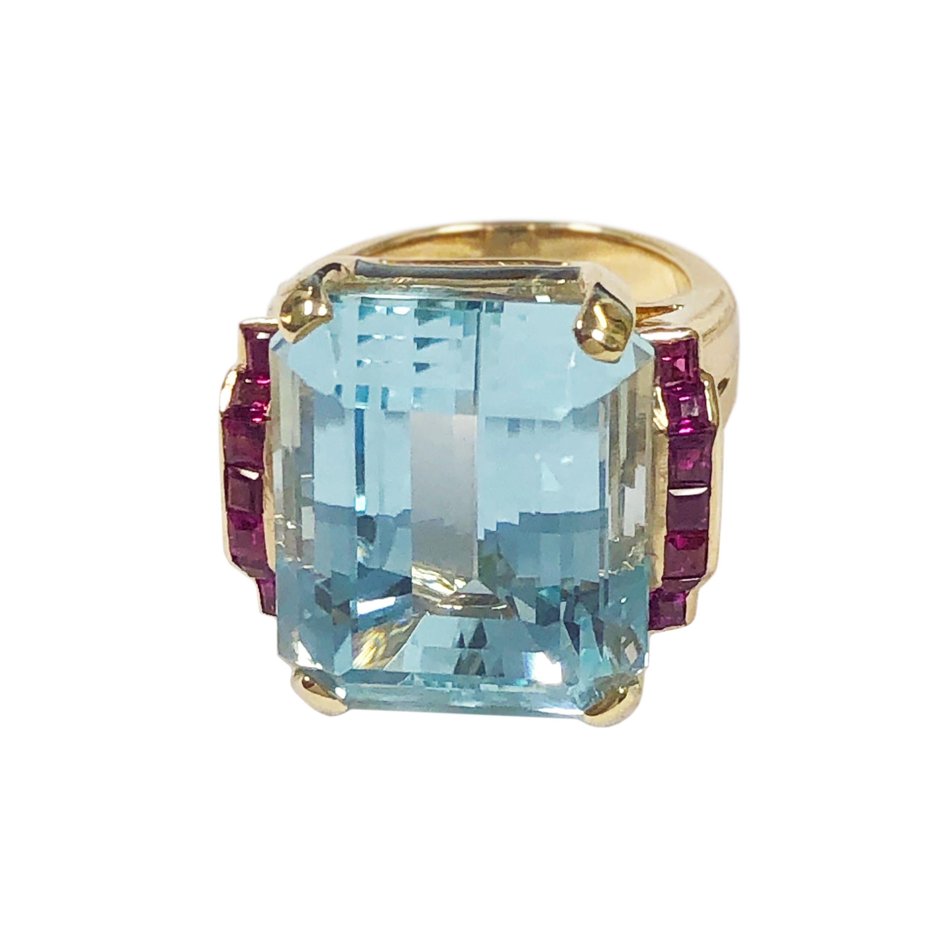 Circa 1940s Retro Aquamarine Ring, 14K Rose Gold and set with a very Fine bright Ocean Blue Step cut Aquamarine measuring 19 X 15 M.M. approximately 14 Carats. Set on either side with Fine color Square step cut Rubies. Finger size 7. Excellent,