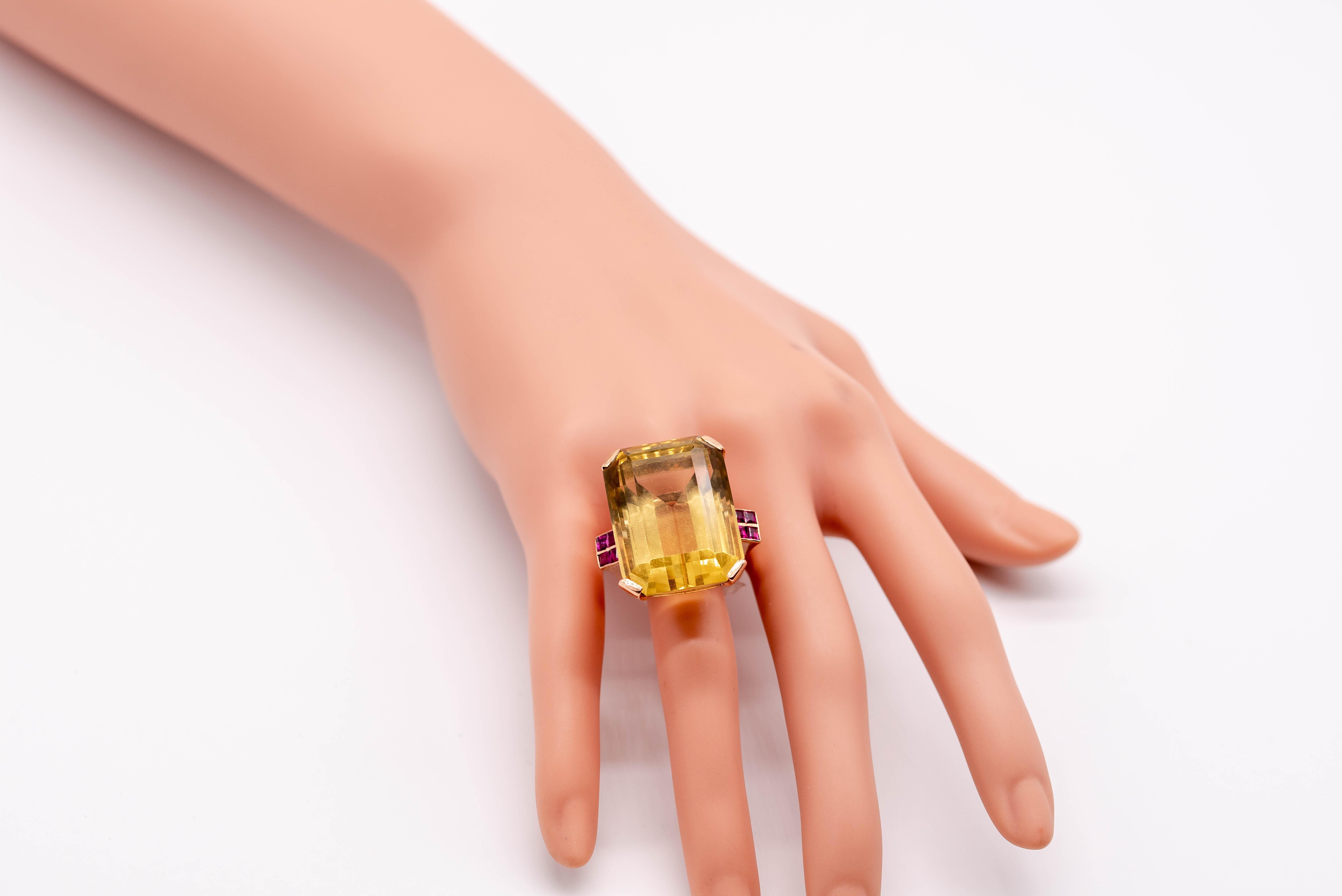 A great example of the cocktail jewels so prevalent in the 1940's, this distinctive ring boasts a large honey colored citrine weighing about 67 carats flanked at the shoulders by square cut rubies, two on each side.  It's a nice contrast in