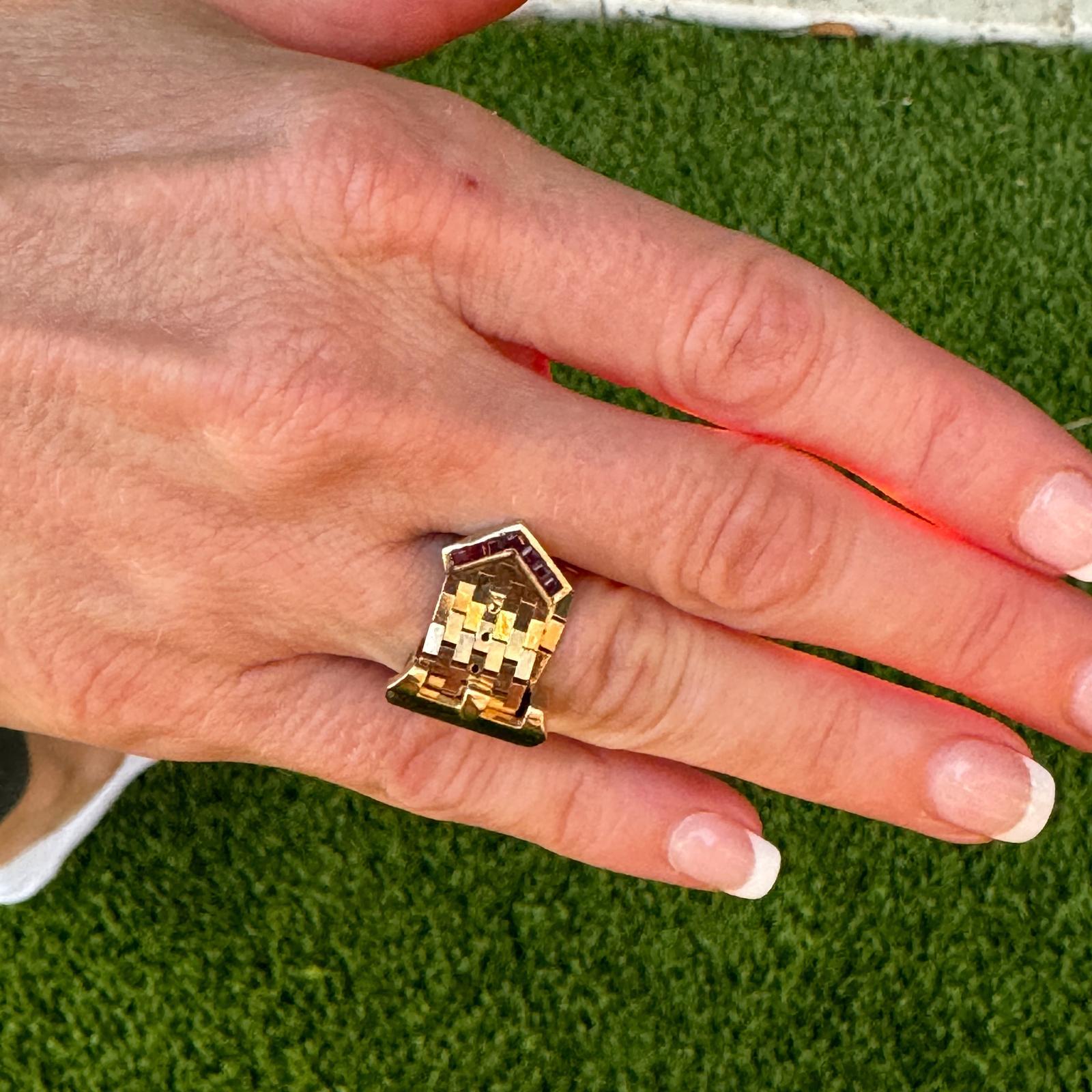 Fabulous Retro buckle ring handcrafted in 14 karat yellow gold. The adjustable ring was crafted with small links, and features ruby accents on the buckle. The ring measures 10mm in width (15mm at the buckle), and can fit ring size 4-10. Weight: 10.9