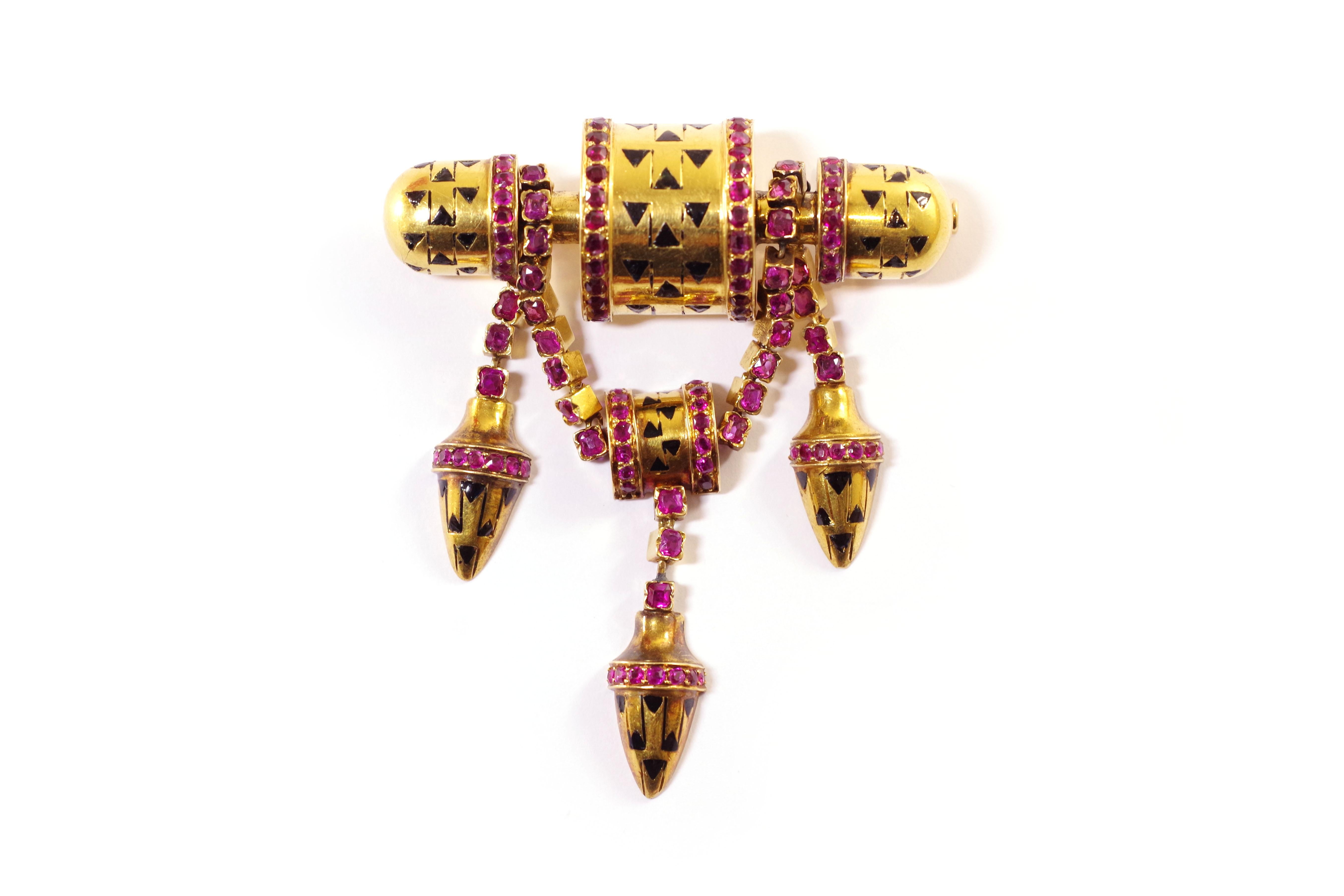 Retro ruby brooch in yellow gold 18 karats. Brooch composed of a bar decorated with three half-cylinders with enamelled black triangles and decorated with lines of rubies. Four chains set with rubies hold three pendants also enamelled with black