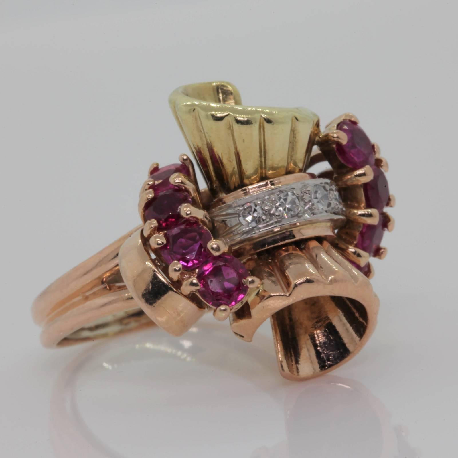 A 1940 Retro beautiful dimensional ring, created in Rose and Green 14KT gold.  The double bow center is gathered by four Single Cut Diamonds, accented on each side with eight Burma Rubies weighing approx. 1.00 carat.   The ring is enhanced with