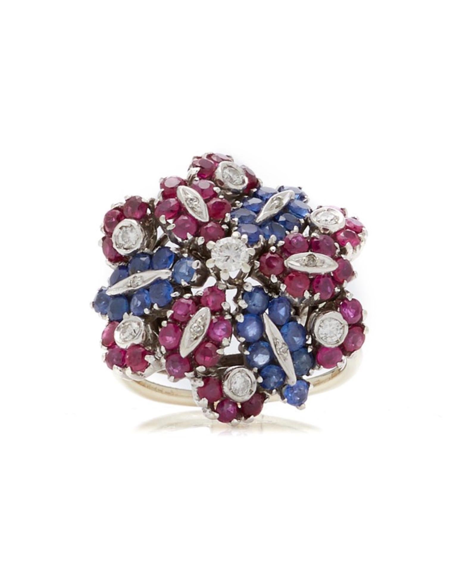 A chic retro flower ring embellished with rubies, sapphires, and diamonds, set in white gold. 