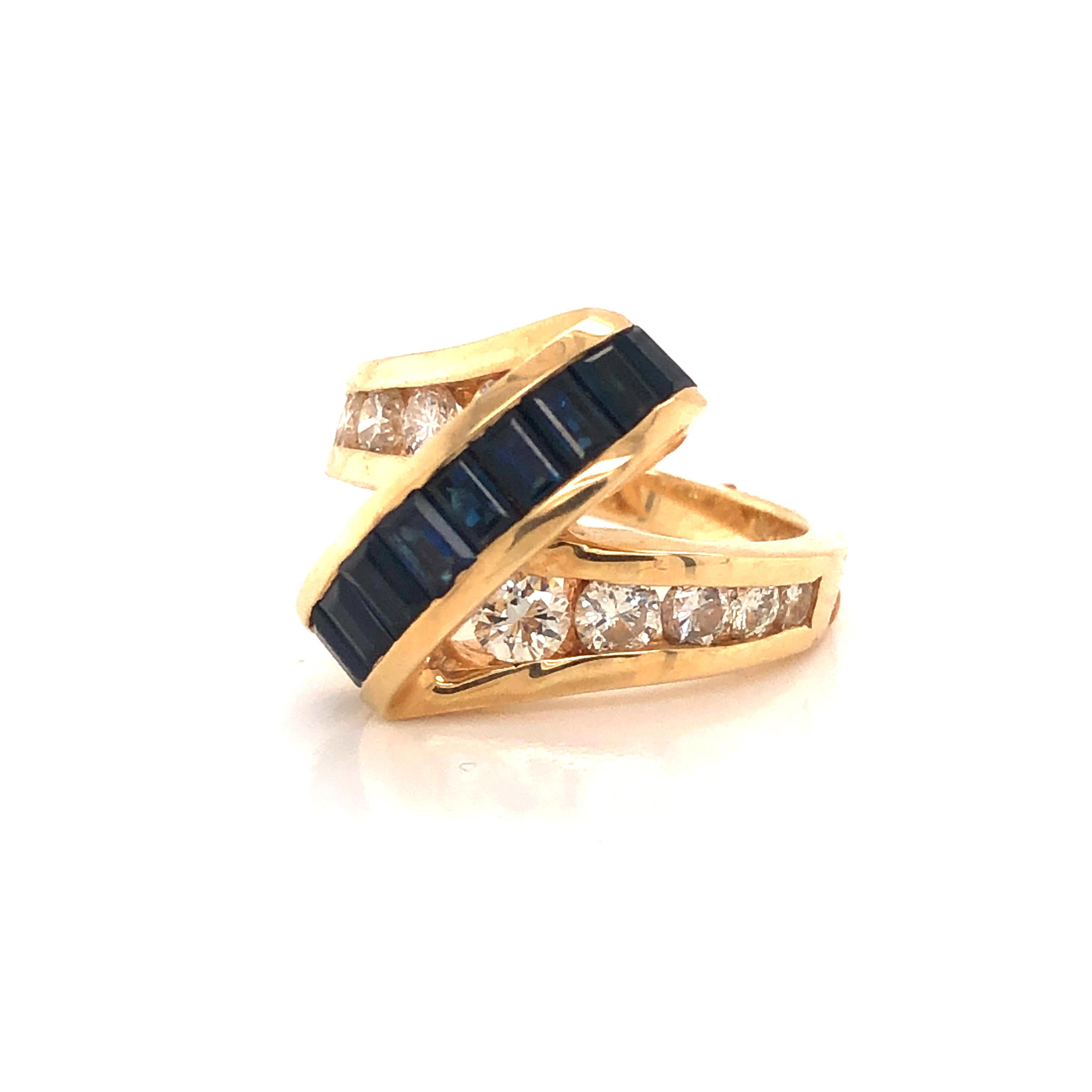 Swirling design on this fantastic cocktail ring crafted in 14k yellow gold. This 3-D styled ring is set with natural sapphires and diamonds that show angles where the gemstones appear raised off the ring. Ten square cut sapphires are set atop the