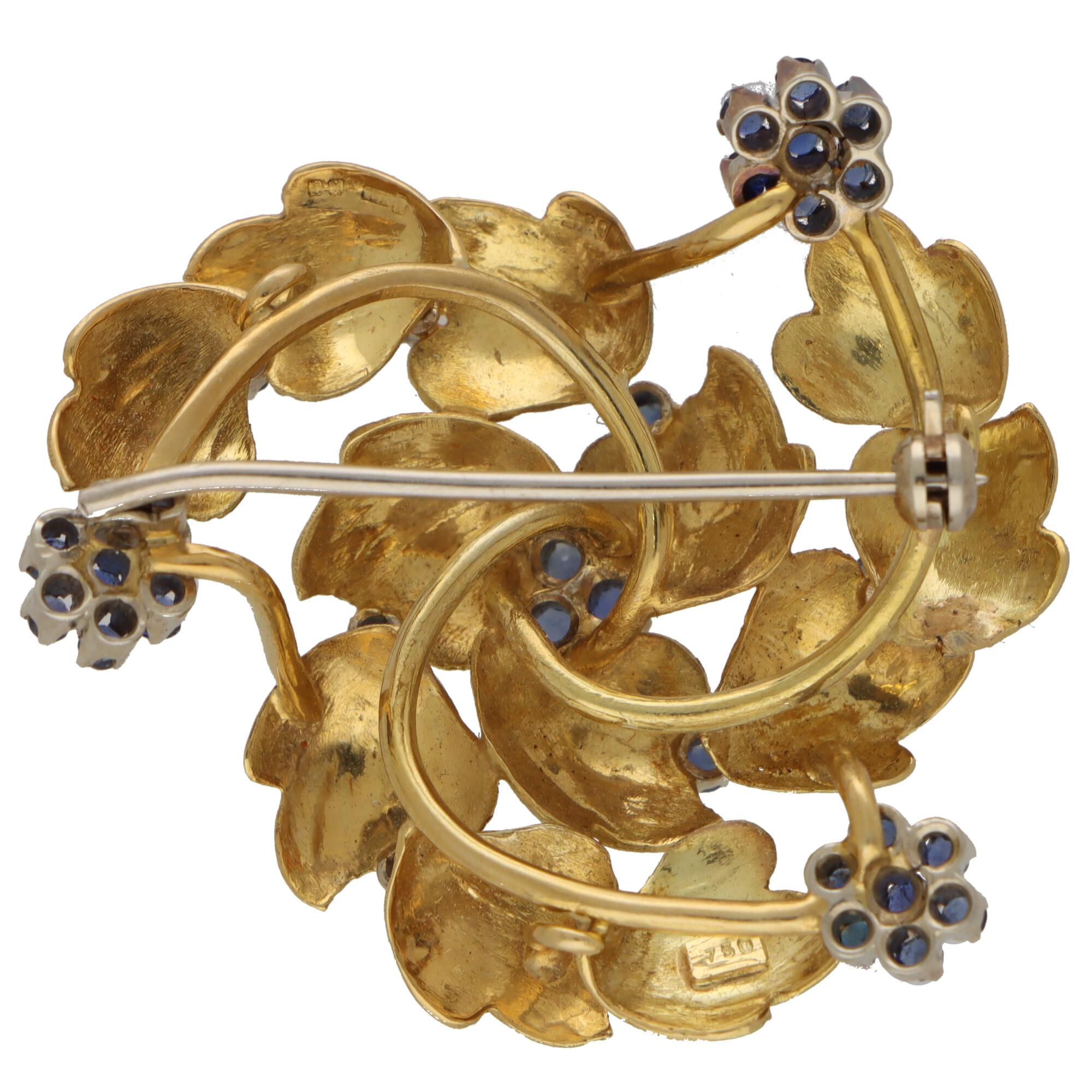 A beautiful retro sapphire swirl brooch set in 18k yellow and white gold. 

The brooch is designed as three swirls surrounding a cluster of three round mixed-cut sapphires. Each swirl component is composed of three consecutive carved leaf motifs