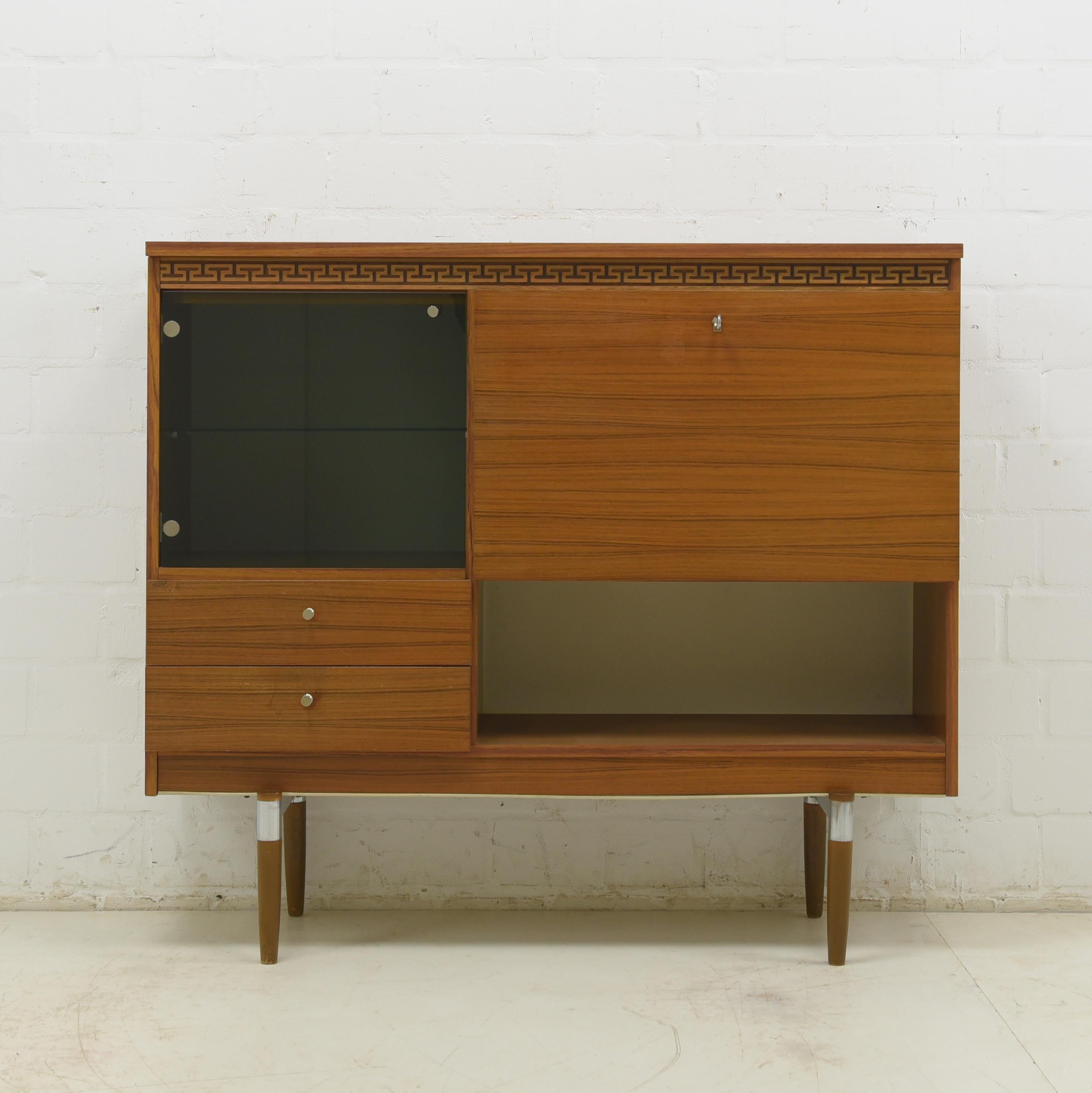 Sideboard restored in the 1970s around 1975/1980 Highboard display cabinet

Features:
Completely original
Asymmetrical fourfold subdivision
With smoked glass door, large folding compartment, two drawers and open compartment
Nice