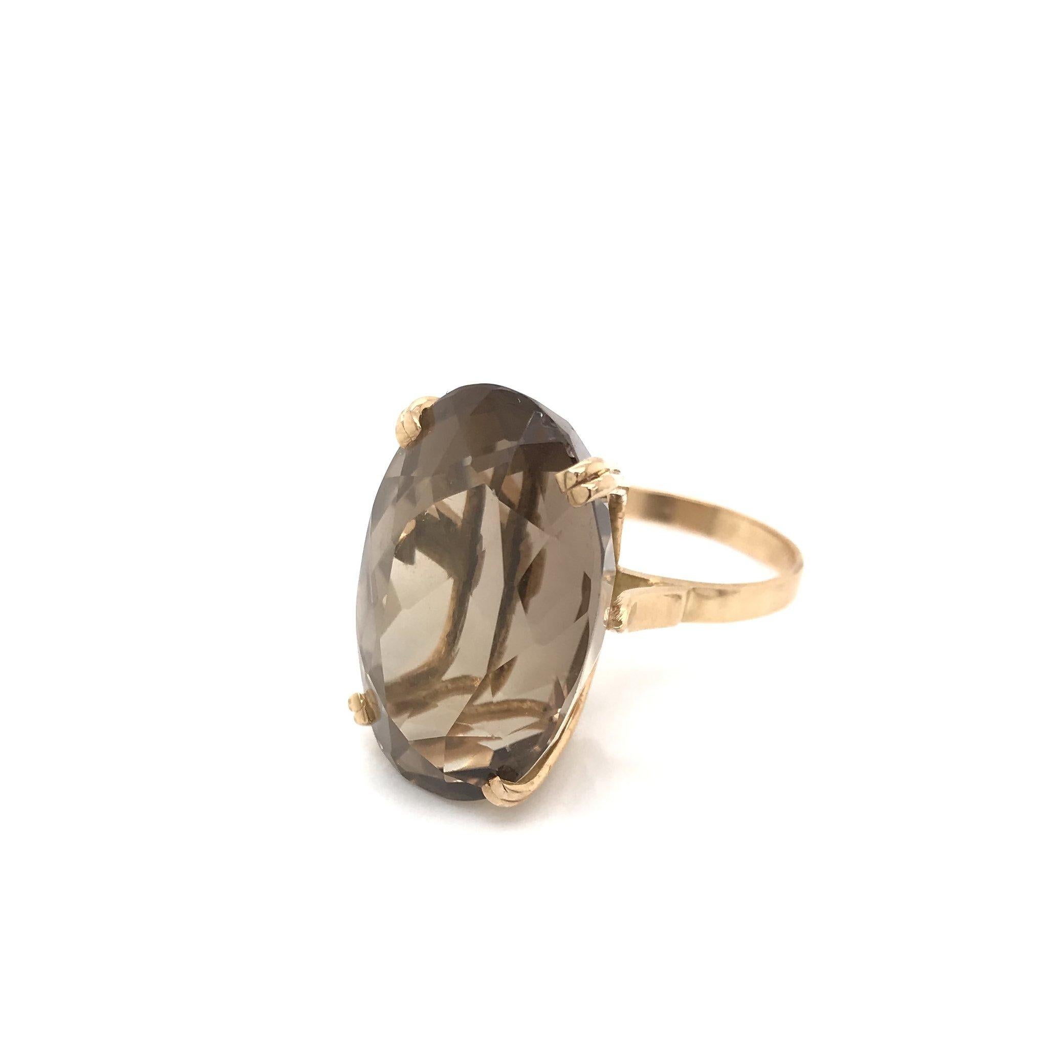 This bold and beautiful cocktail ring was crafted sometime during the Mid Century design period ( 1940-1960 ). The simple solitaire setting is 18k gold and features a large fancy cut smoky quartz. During the Mid century period smoky quartz was