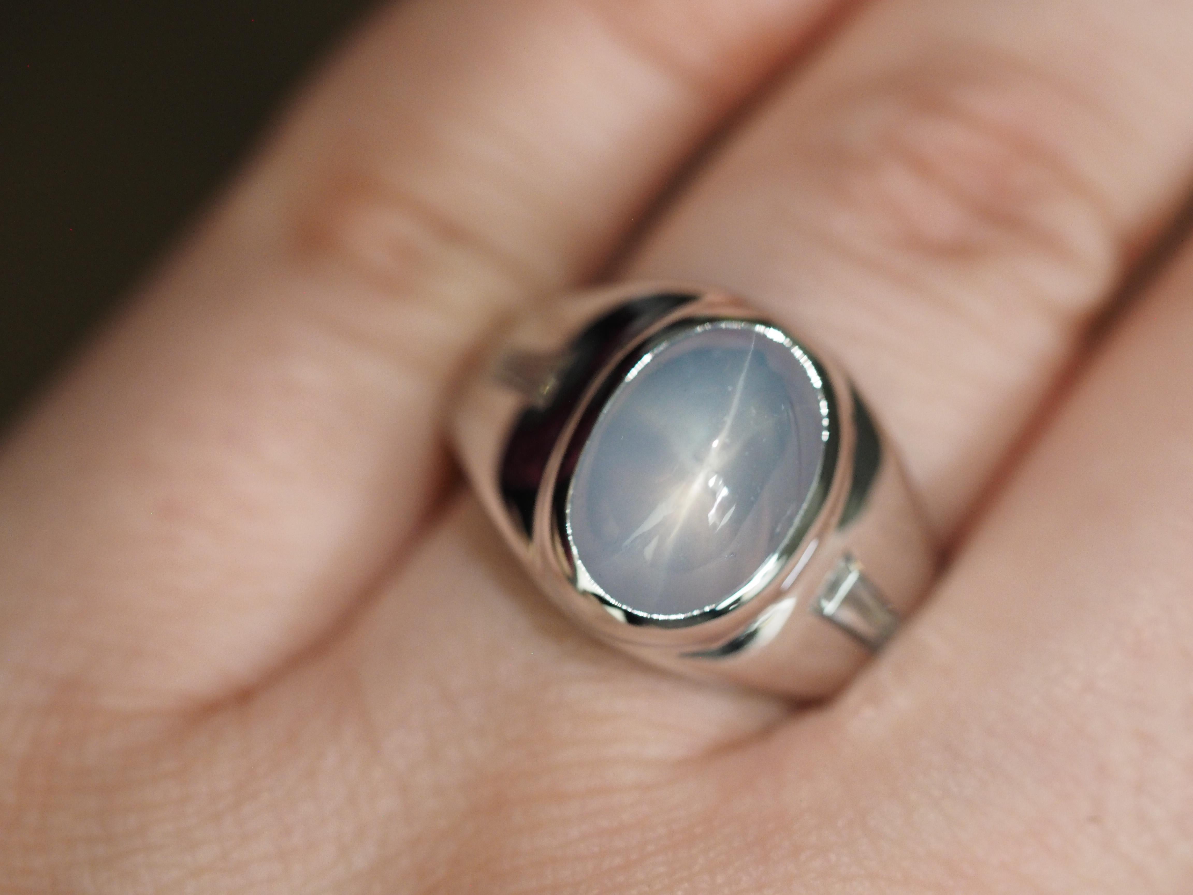 This Retro Star Sapphire and Diamond 14K White Gold Ring dates back to the 1980's. The optical phenomenon is very visible in this star sapphire. The center measures 12.2 x 8.4mm. There are two bezel set baguettes one on each side measuring 5.7 x 2.8