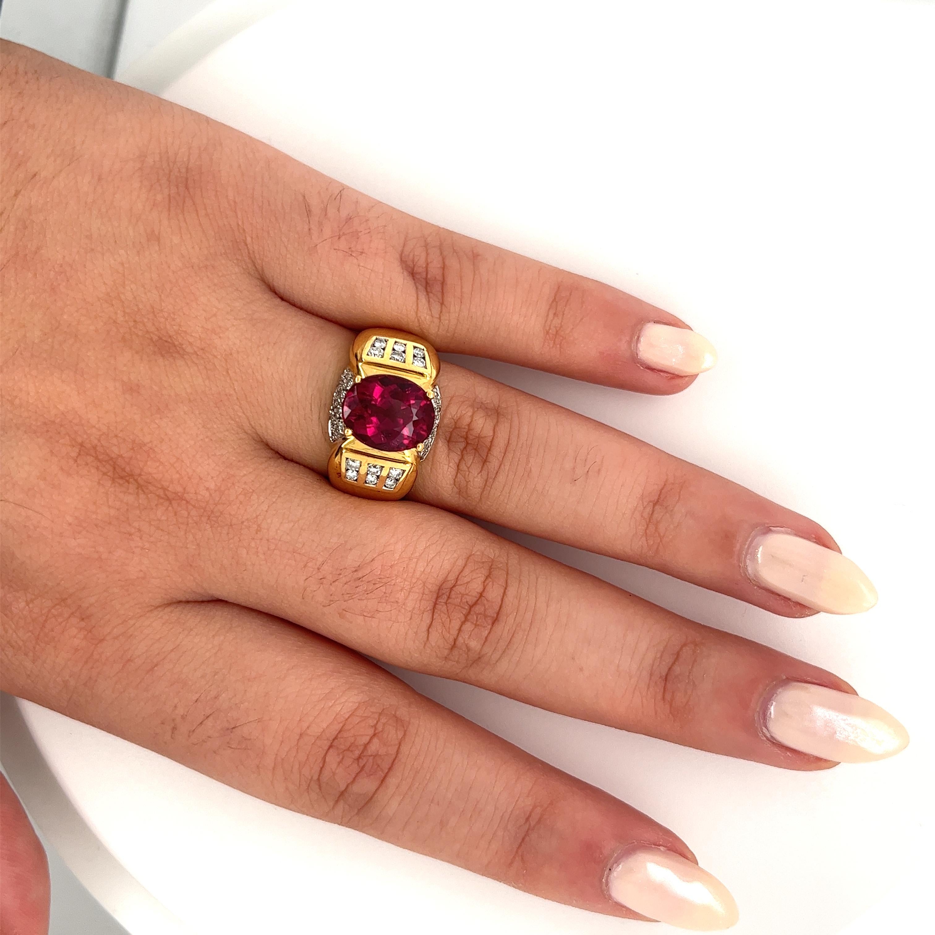 Vintage semi-precious gemstone ring, featuring a natural oval cut rubellite tourmaline center stone, weighing approx. 4.50 carats. Paired with channel set round cut diamond side stones, this ring boasts a vintage feel with its two-toned 18k yellow