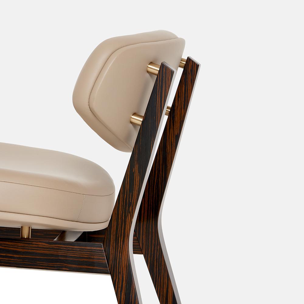 Este sillón artesanal encarna una fusión perfecta de estilo y comodidad. Su robusta estructura de madera maciza se complementa con una lujosa tapicería de piel en un sofisticado color latte. Las patas, fabricadas con chapa de madera de ébano y
