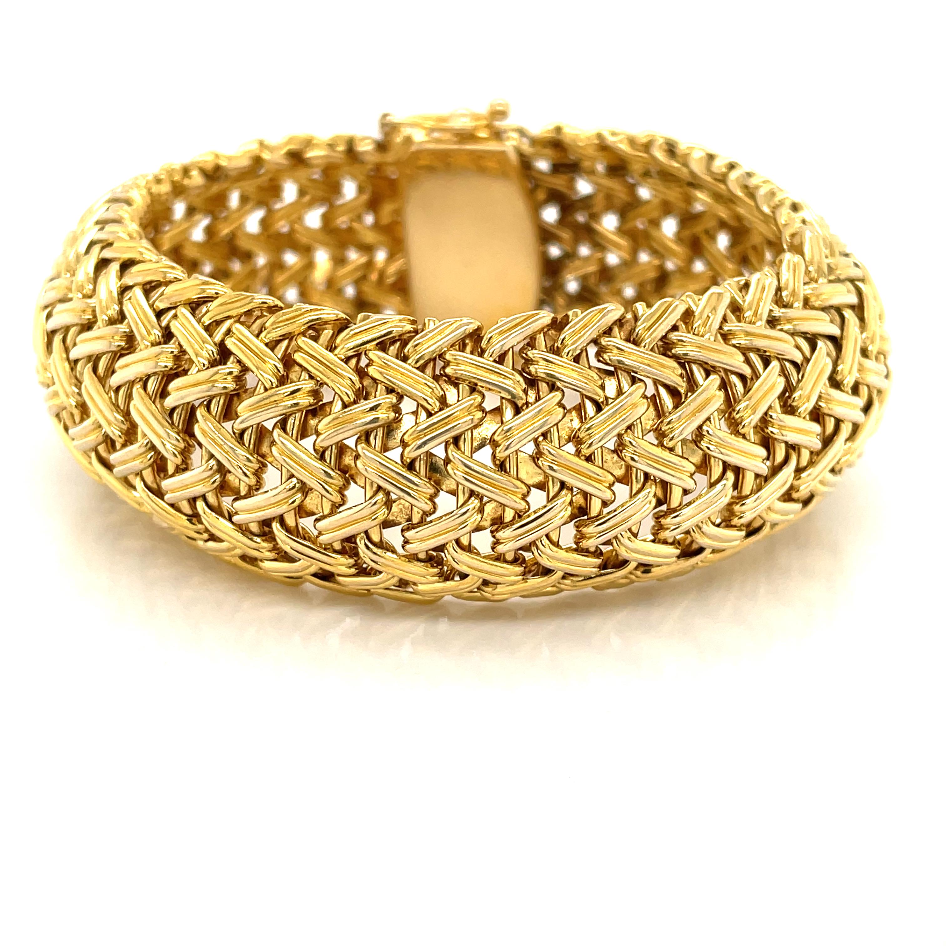 Striking in woven fourteen karat 14K yellow gold, this uniquely contoured bracelet is a pinnacle retro style and certainly coveted and relevant today. Of generous weight with an emphasis on quality craftsmanship,  this stunning bracelet presents a