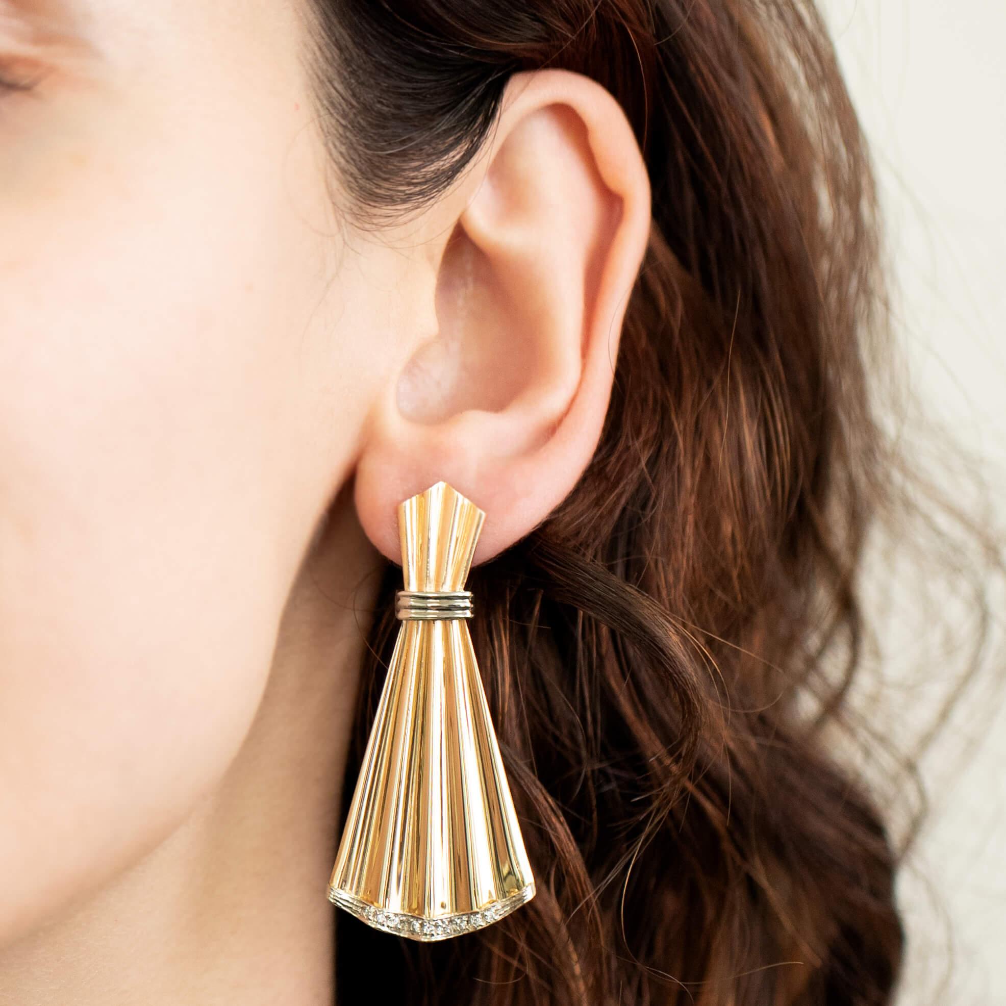 One pair of long hinged 14k two-tone gold drop earrings. Portraying the ‘Retro’ style fluted fans featuring a band of small brilliant cut diamonds on the ends. Fitted with a post and butterfly for secure wear.

Diamond: Sixteen small round brilliant