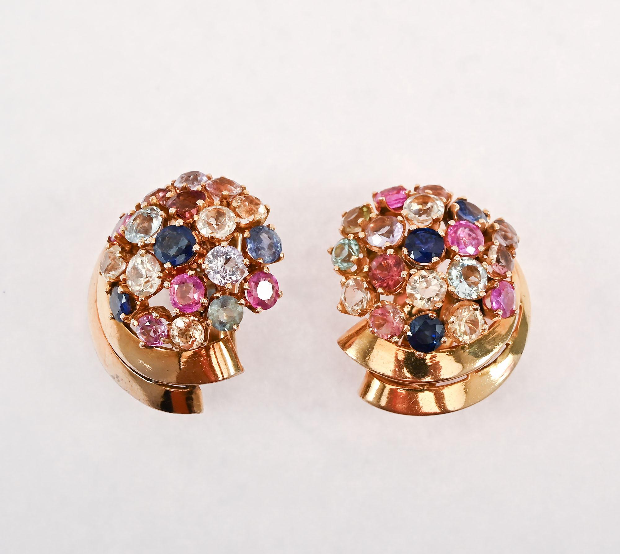 Questi coloratissimi orecchini multigem sono in pieno stile retrò, ma probabilmente sono stati realizzati negli anni '60. Due file di fasce curve in oro 14 carati abbracciano il gruppo di pietre composto da zaffiri, acquamarina, tormalina e topazio.