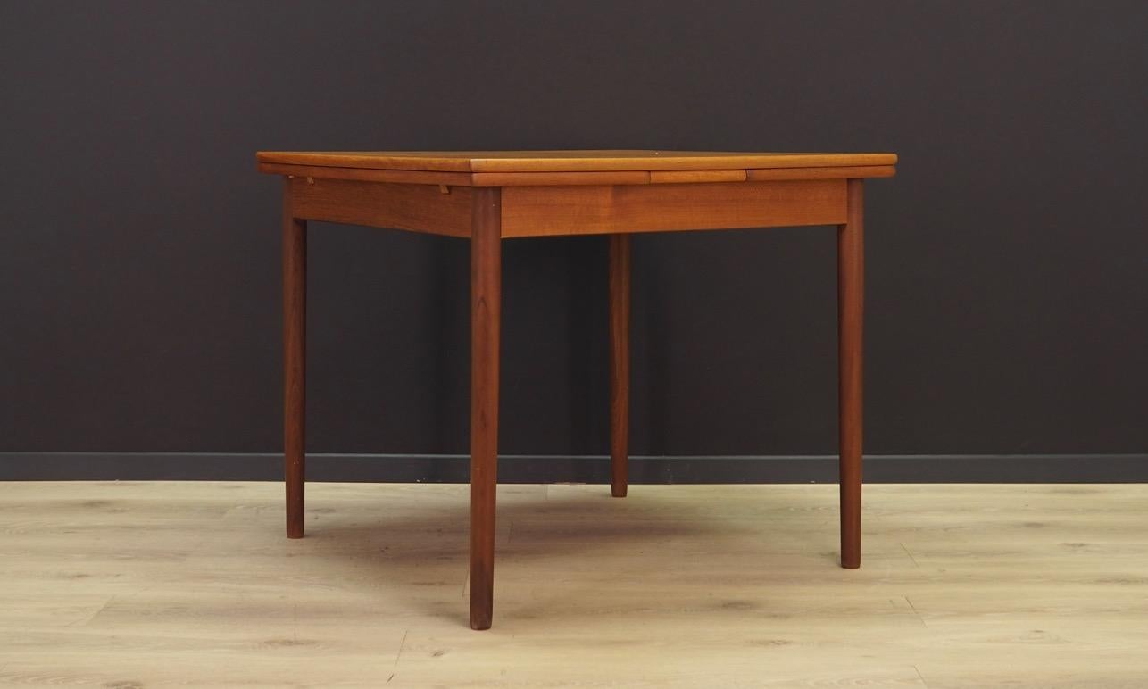 Sensational dining table from the 1960s-1970s. Scandinavian design, Minimalist form. Table top finished with teak veneer, construction made of solid teak wood. The table has two pull-out inserts under the table top. Maintained in good condition