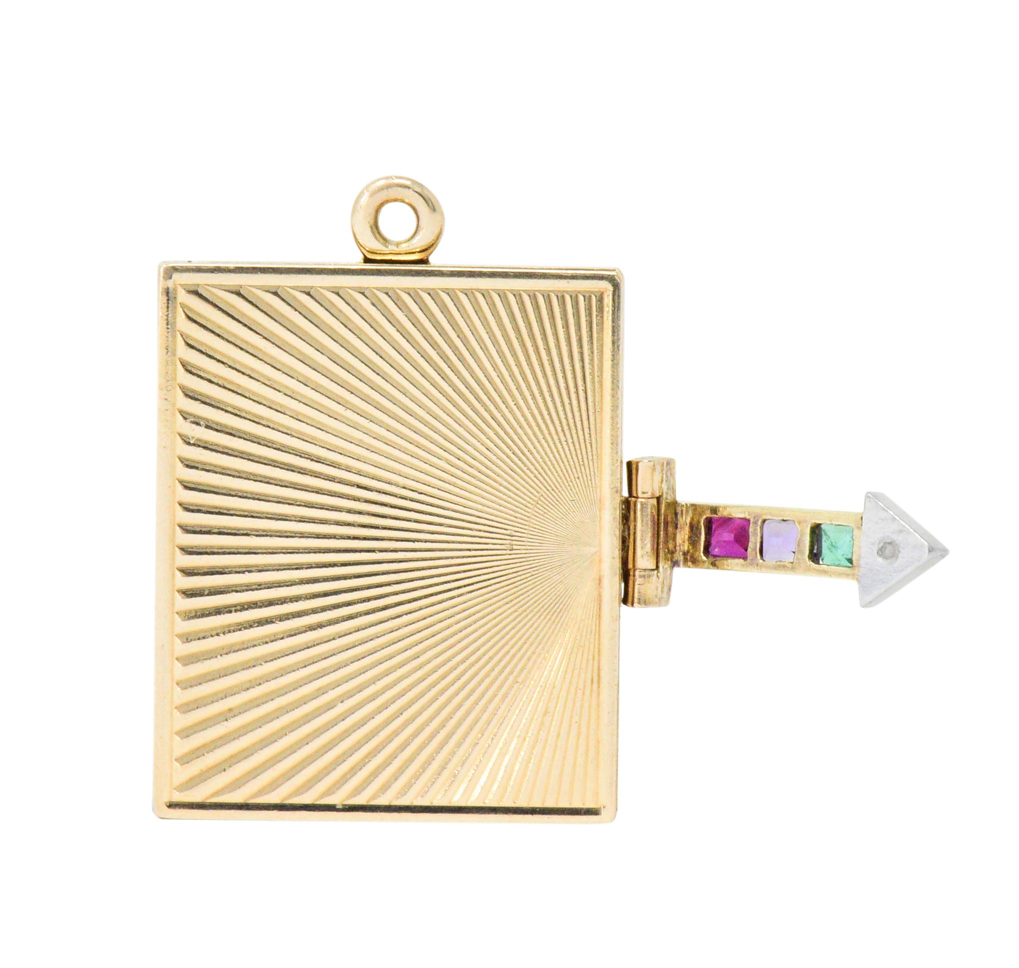 Designed as opening book with radiating ribbed gold on cover and back

Swinging arrow shaped closure set with round brilliant cut diamond and channel set straight baguette amethyst, emerald, and ruby, spelling out the word 'DEAR'

Opens to reveal