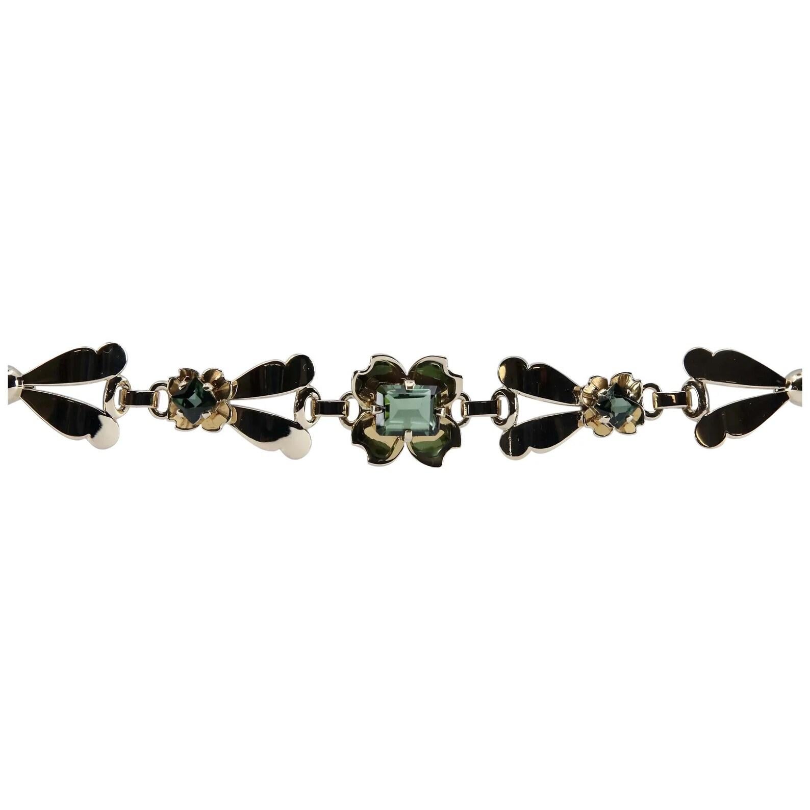 A vintage Tiffany & Company retro four leaf clover green tourmaline bracelet in 14 karat yellow gold. Centering this bracelet is a four leaf clover set with a rectangular 3 carat green tourmaline. Framing the center flower are stylized yellow gold
