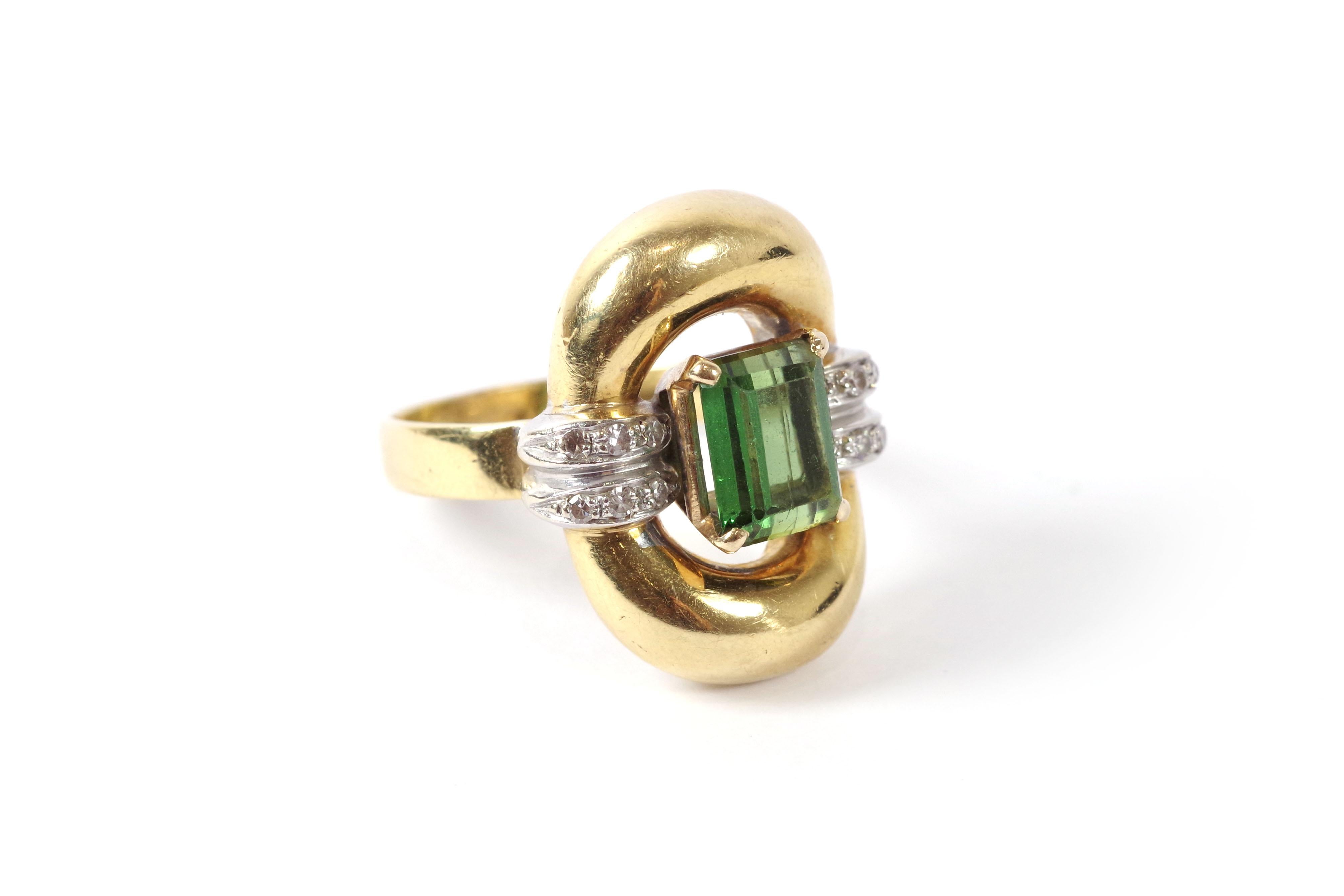 Retro tourmaline gold ring in 18 karat yellow gold. Vintage ring with an oval and domed top centered with a green tourmaline, also known as verdellite, set with four prongs. The ring's shoulders are adorned with two rows of platinum set with twelve