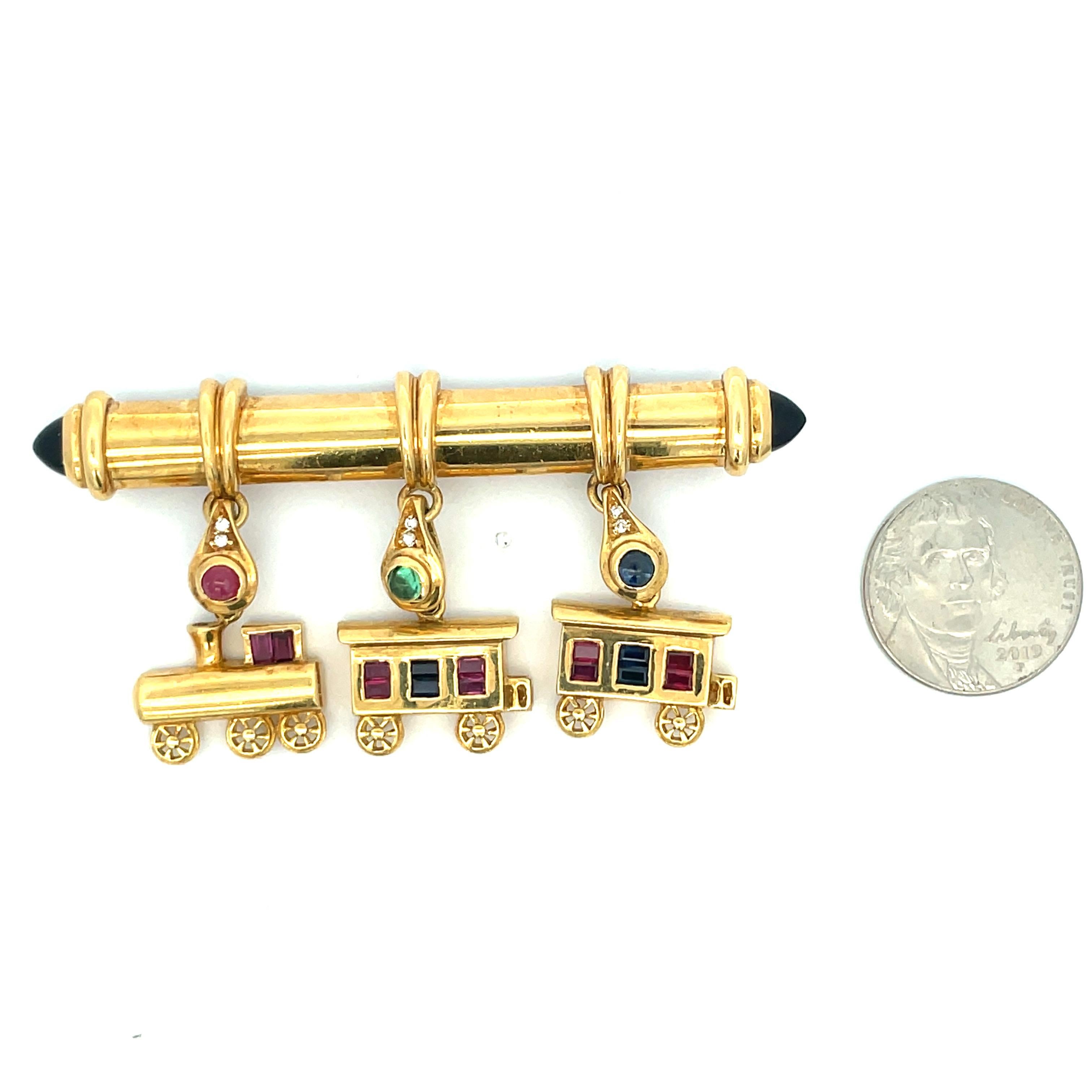 Adorable Retro brooch featuring a series of trains with accents of Sapphires, Emeralds and Rubies crafted in 18 Karat Yellow Gold. 