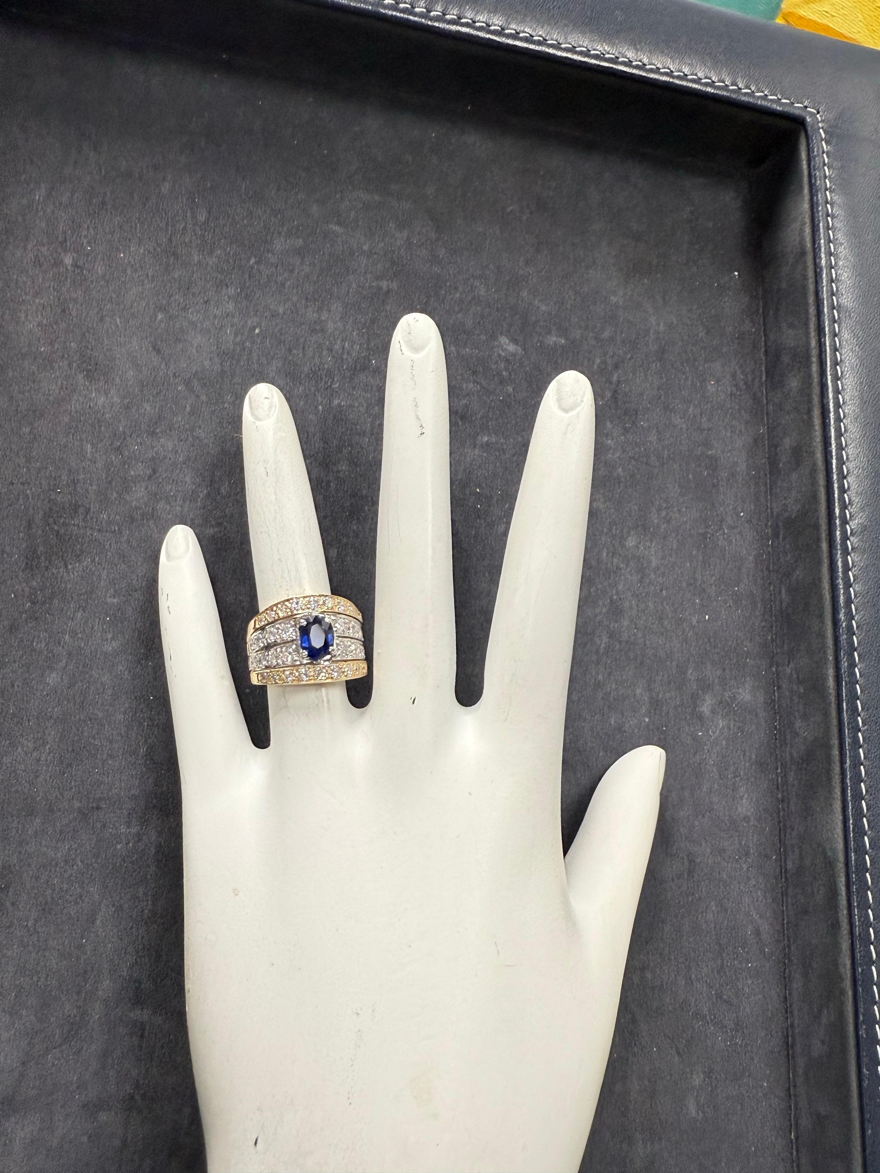 Elegant retro two-tone 14 karat white and yellow gold cocktail ring set with a natural royal blue sapphire and colorless round brilliant diamonds. At the center rests a deep royal blue oval sapphire measuring approximately 7 × 5.5 × 3.4 mm, weighing