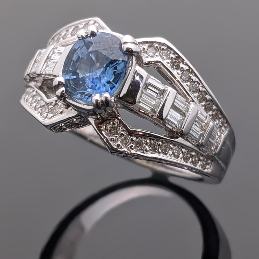A vintage 14kt white gold ring featuring a radiant blue center sapphire with an estimated weight 0.59ct. surrounded by baguettes and brilliant cut diamonds with an estimated 0.61 cttw. Estimated weight of gold 5 gr. 

We will size it for you.

