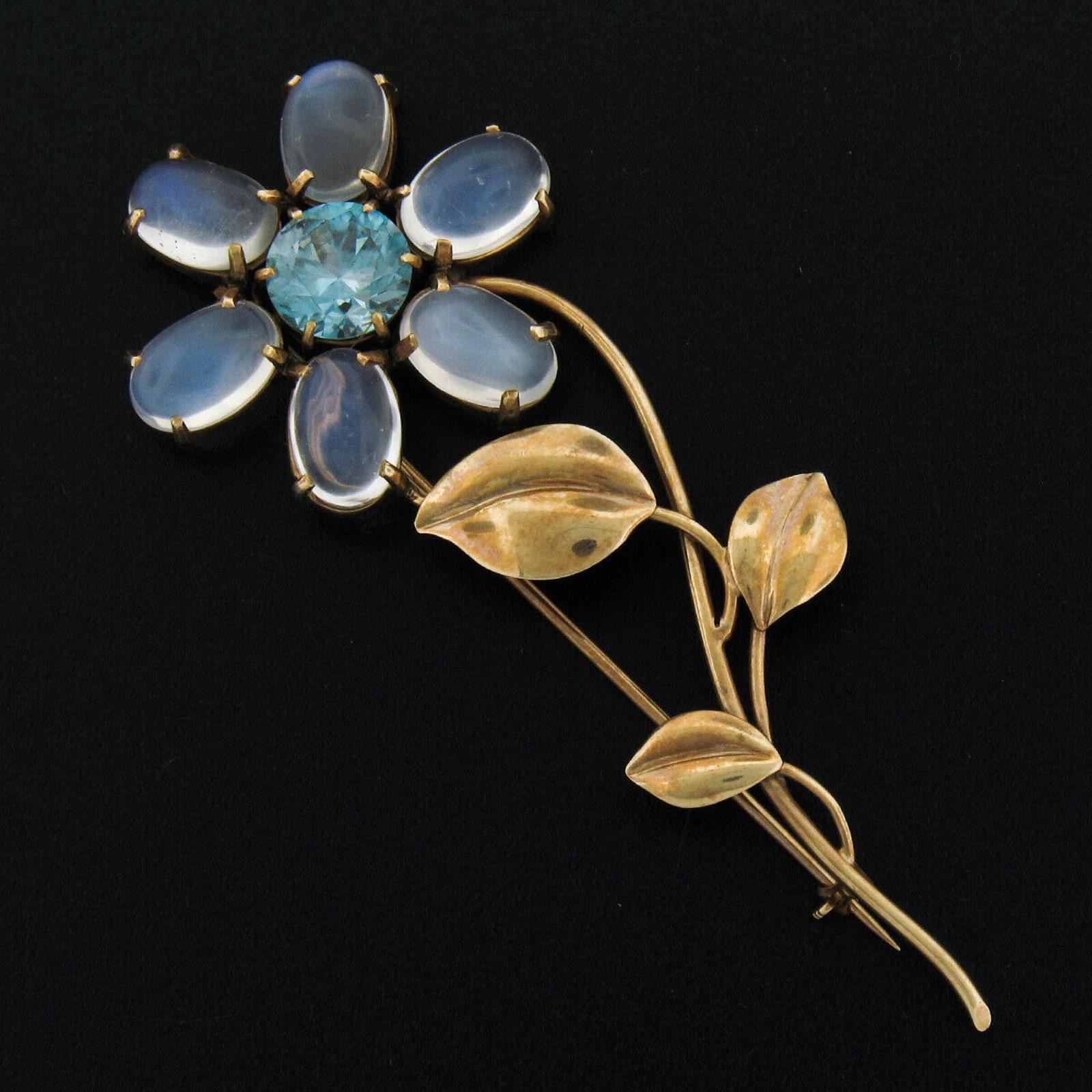 This elegant retro vintage brooch is crafted in solid 14k yellow gold and features a jaw-dropping round cut blue zircon which displays a very attractive and vivid blue color. It is prong set at the center of the flower design and is then surrounded