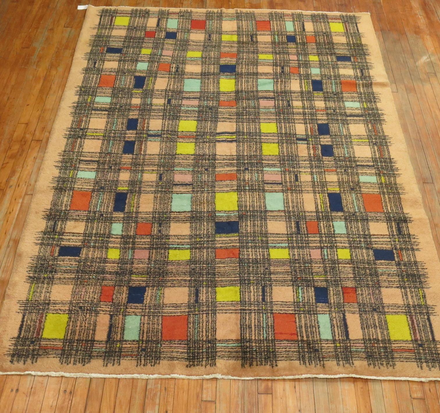 A handmade midcentury Turkish retro style rug with a square thin line repetitive design in multiple colors on a pink-bone colored ground. Bright yellow, corals, teal, navy blue make up some of the accent colors.

Third quarter of the 20th century,