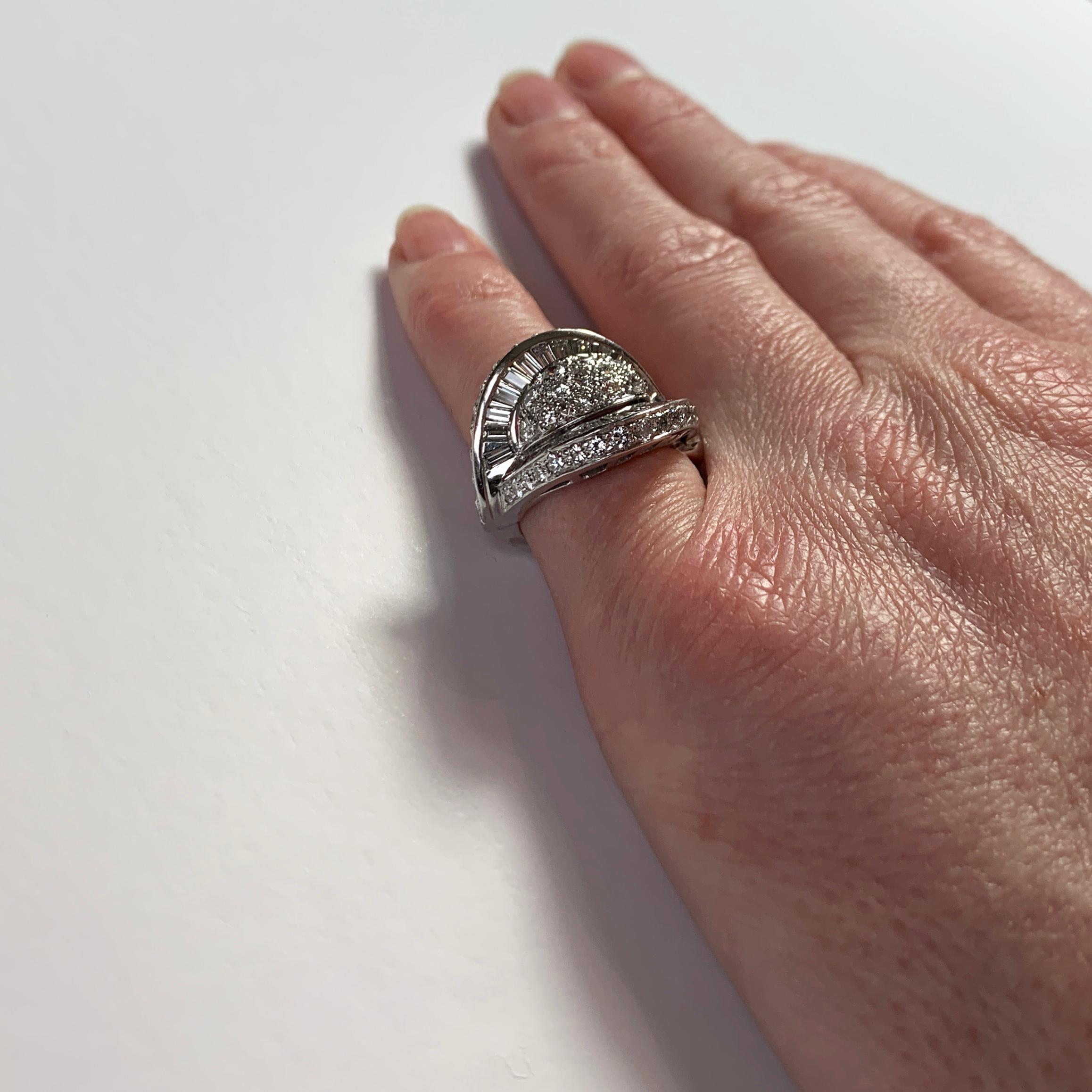 A platinum and white diamond cocktail ring designed as a dome with curved and flaring ridges to each side, set with 47 round brilliant cut white diamonds and 26 tapered baguette diamonds. Unmarked but tested for platinum.

Ring size: 3.5 (US), G