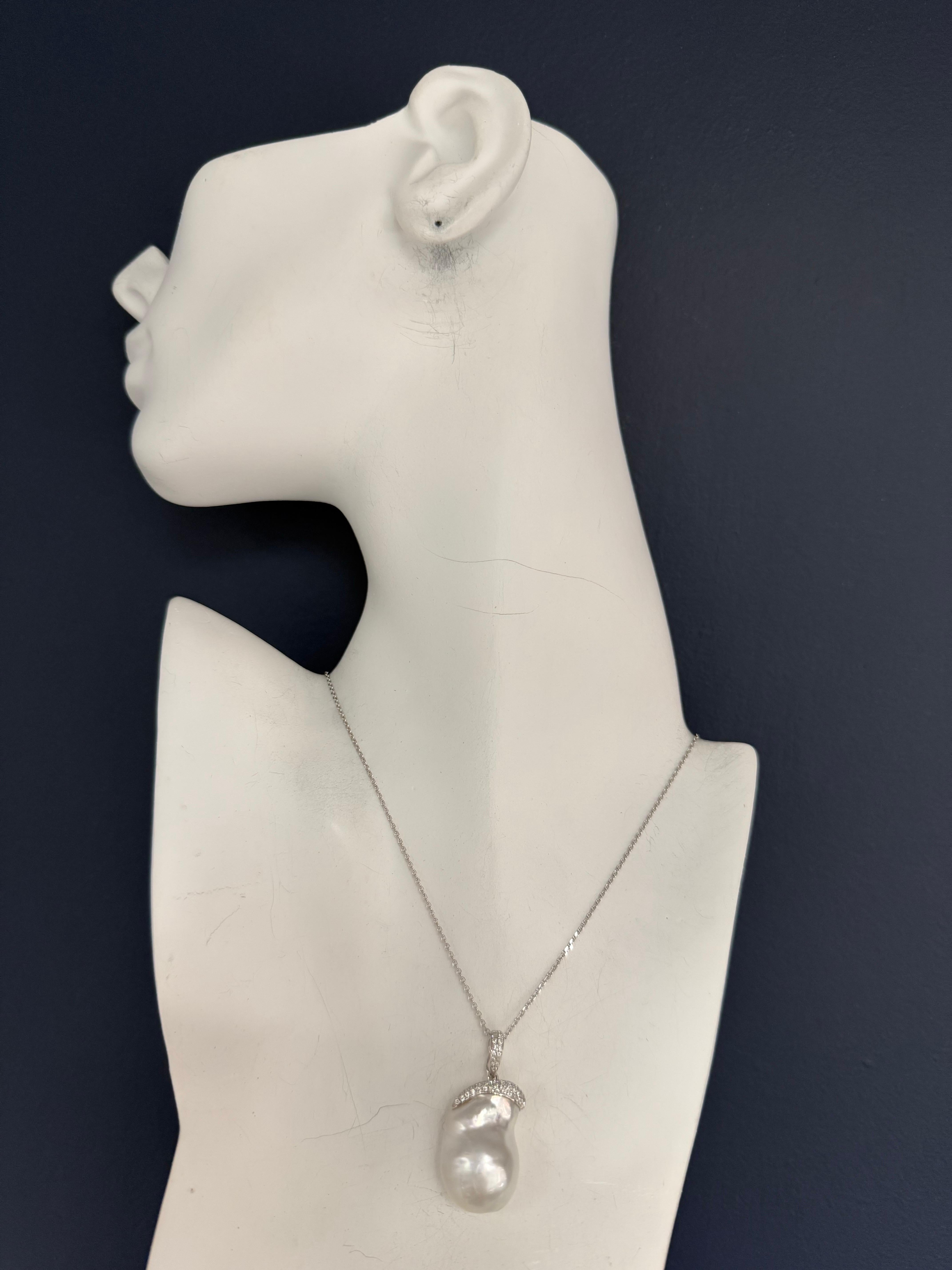 Elegante pendente retrò in oro bianco con incastonata una perla barocca australiana bianca dei Mari del Sud di eccellente lucentezza. La perla misura circa 25 mm di lunghezza e 17 mm di larghezza e il pezzo pesa 13 grammi (senza la catena). 

Il