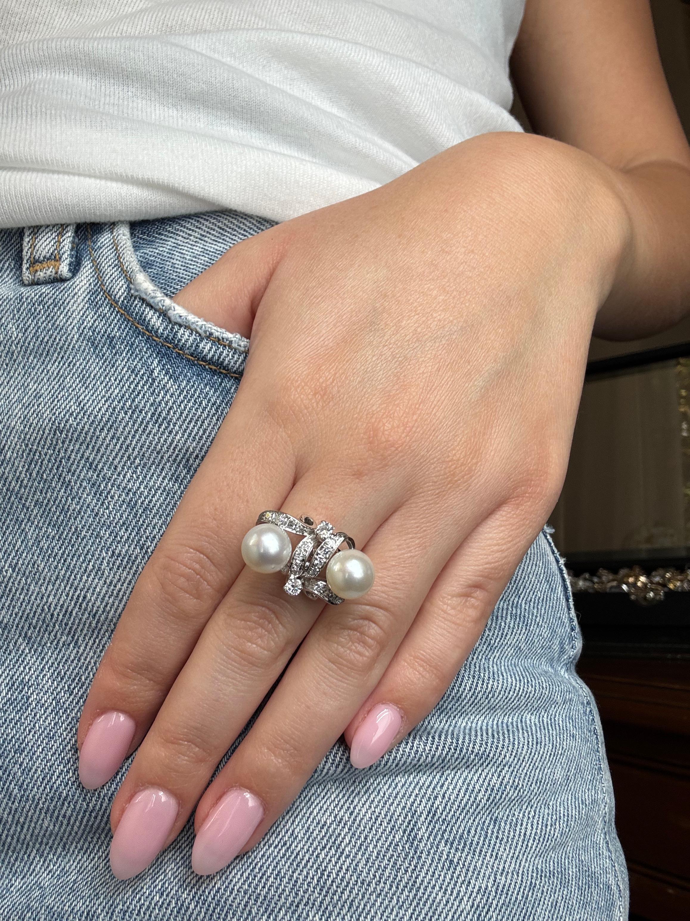 Discover a Retro White Gold Pearl and Diamond Cocktail Ring, a striking mid-20th-century statement piece. Crafted in 18k white gold, this ring showcases two lustrous round pearls entwined in a ribbon-like gallery paved with brilliant-cut diamonds.