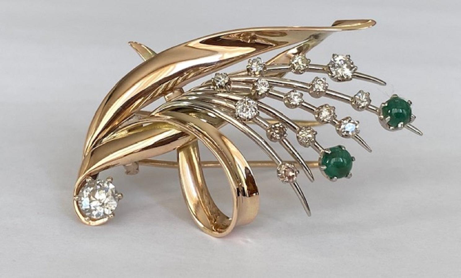 The Retro  brooch is made of 14 kt yellow gold and set with 14 Bolshevik cut diamonds in total approx. 0.65 ct H/SI/P, and one  Bolshevik cut diamond approx. 0.44 ct H/P1 and two cabochon cut emeralds approx. 0.50 ct. total. 
Grade: hallmarked